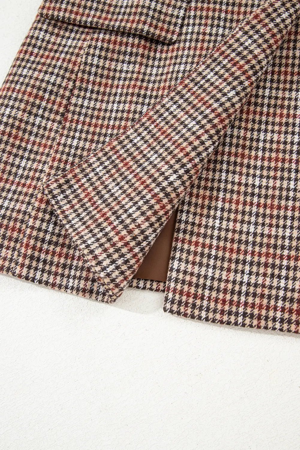 Close-up of a plaid fabric with brown, black, and white pattern on a white background
