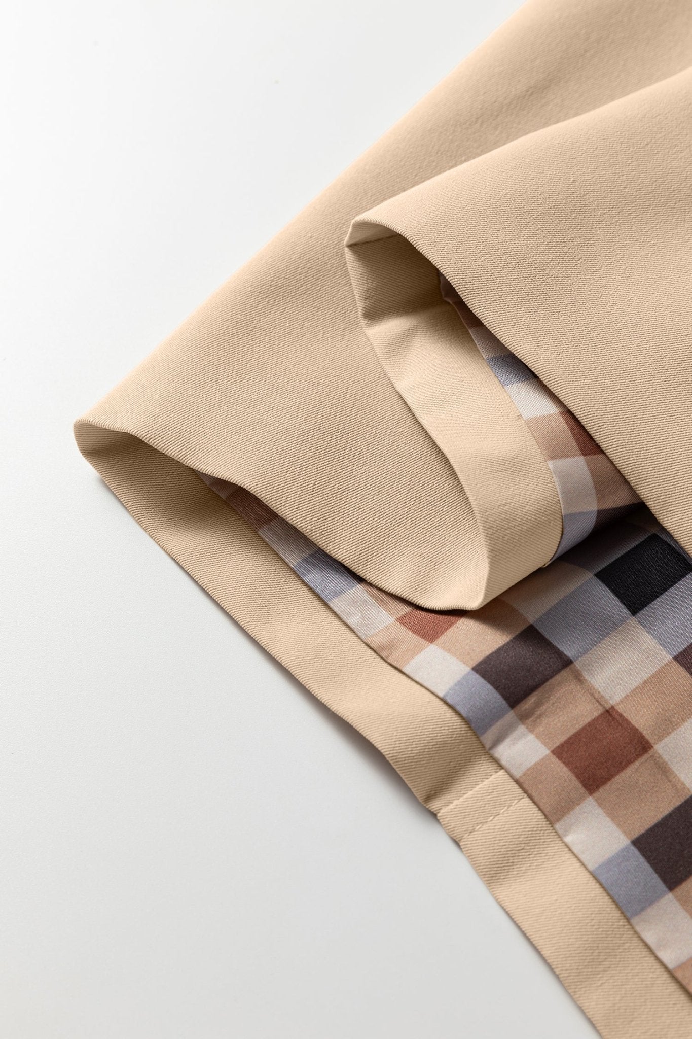Close-up of beige fabric with plaid pattern on a light gray background