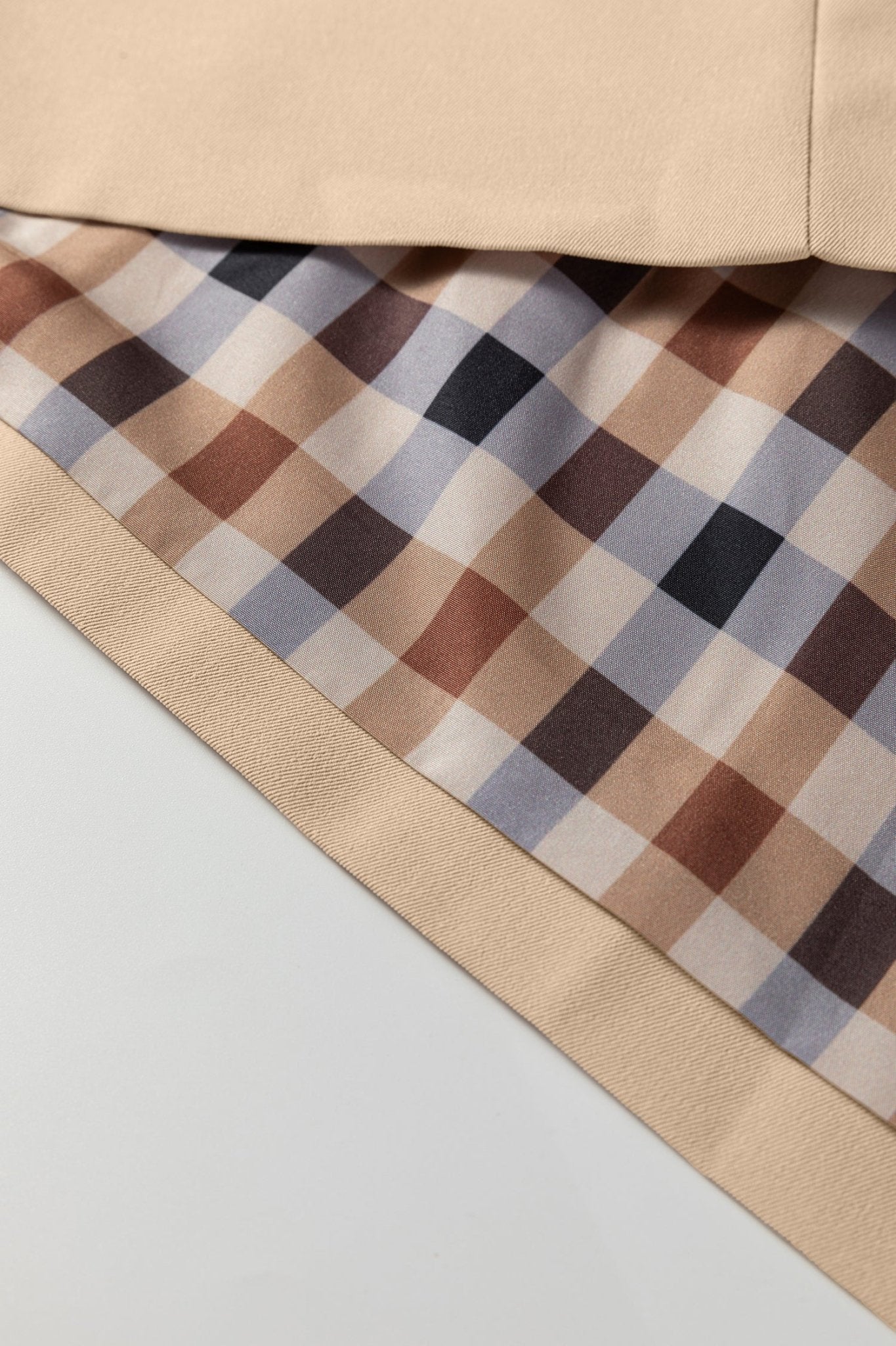 Close-up of a checkered fabric with a beige border on a light gray background