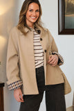 Woman wearing a beige coat with plaid cuffs indoors