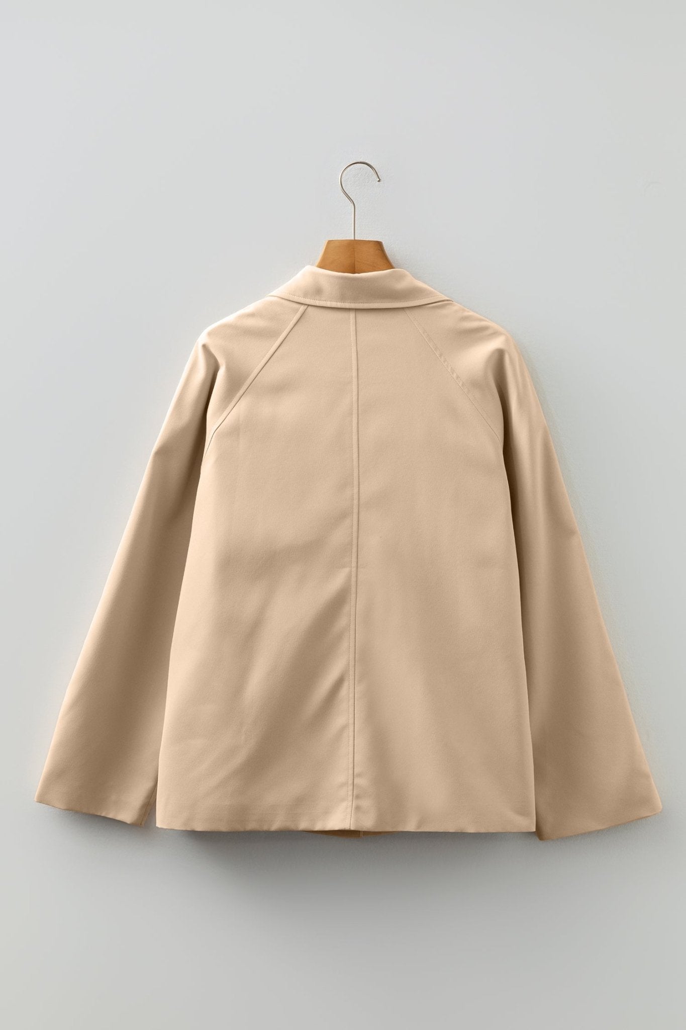 Beige cape on a hanger against a light gray background