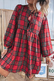 Woman wearing a red plaid long-sleeve dress with tie-front waist and tan boots.