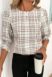 Woman wearing a plaid shirt holding a coffee cup against a light background