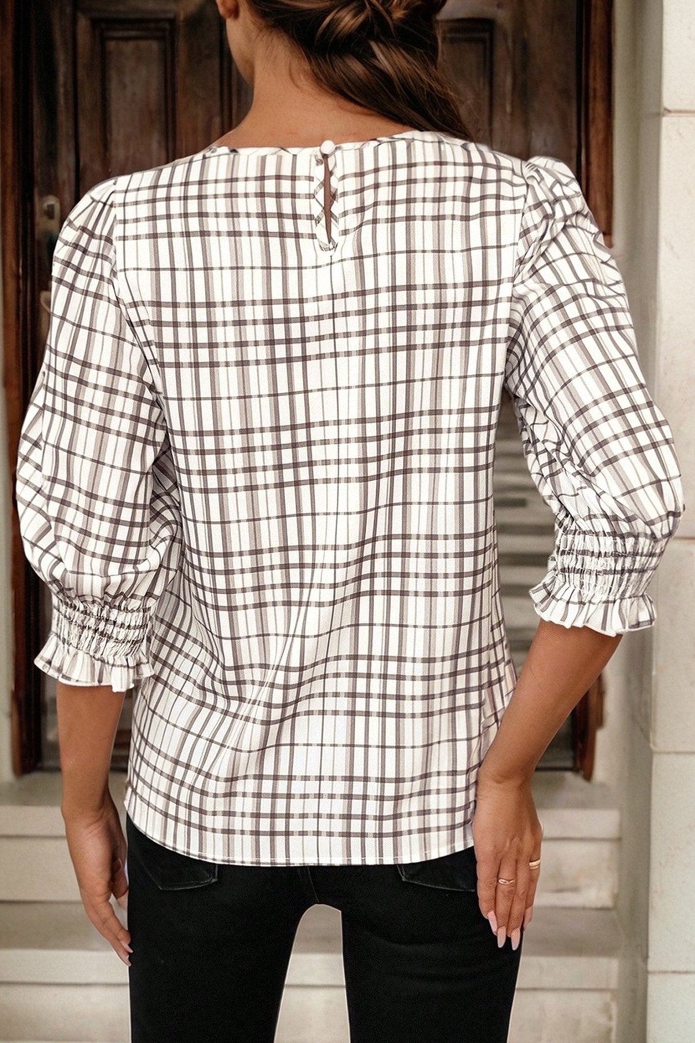 Person wearing a checkered blouse with long sleeves in an indoor setting