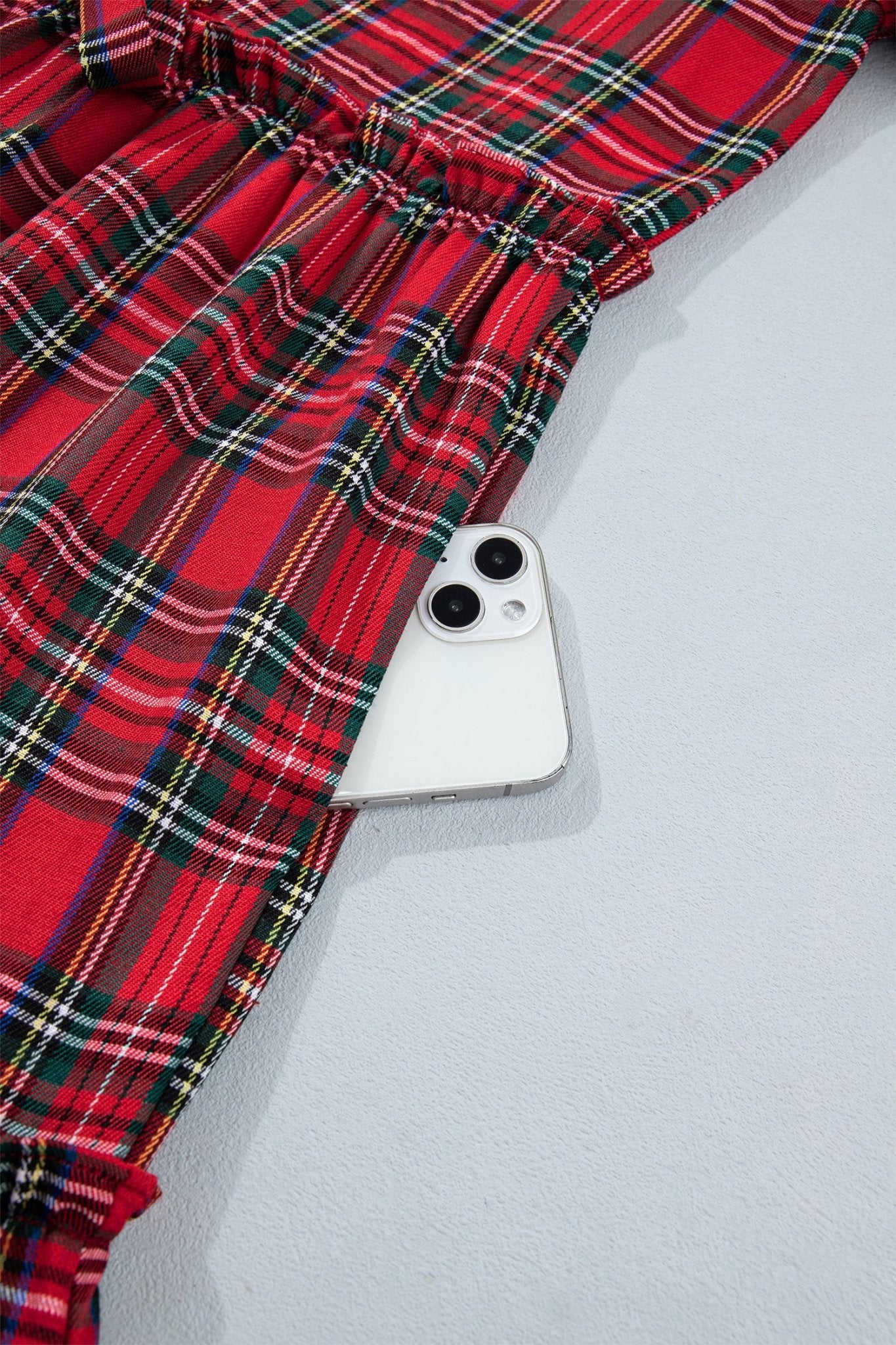 Red tartan plaid garment with a white smartphone in pocket.