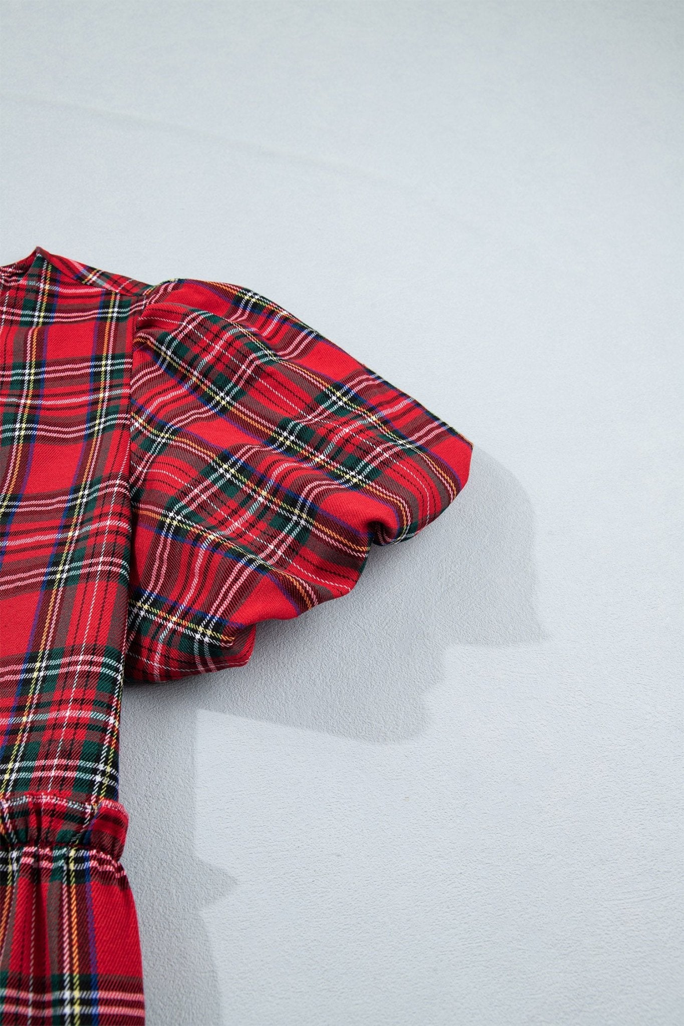 Red tartan garment with puff sleeves and gathered cuffs.