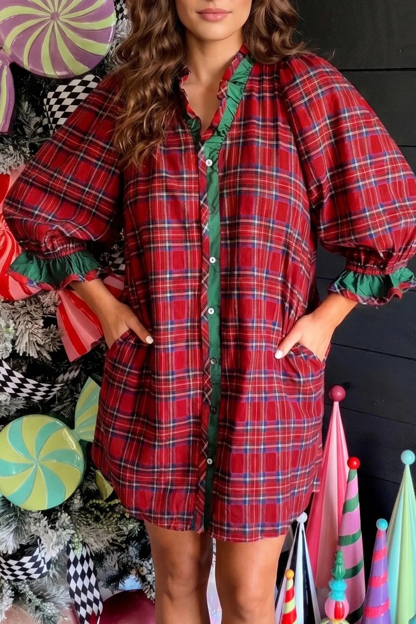 Woman in red-green plaid button-up dress with ruffled trim in holiday setting.