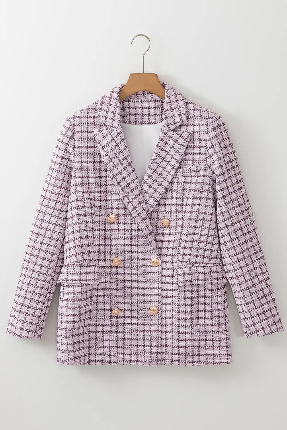 Plaid blazer on a hanger against a white background
