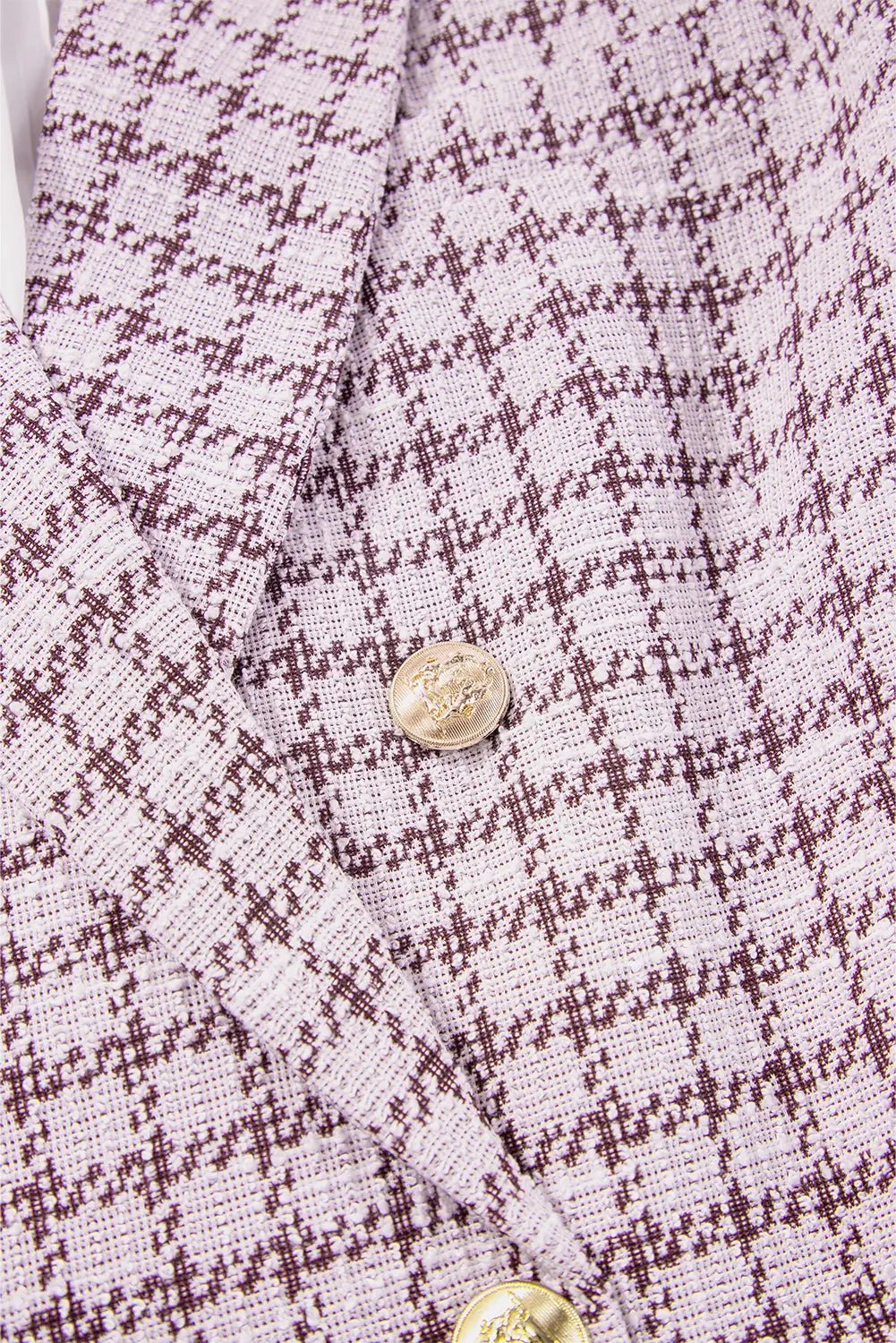 Close-up of a textured fabric with a checkered pattern and gold buttons.
