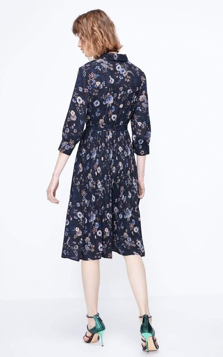 Woman wearing a navy floral dress on a white background