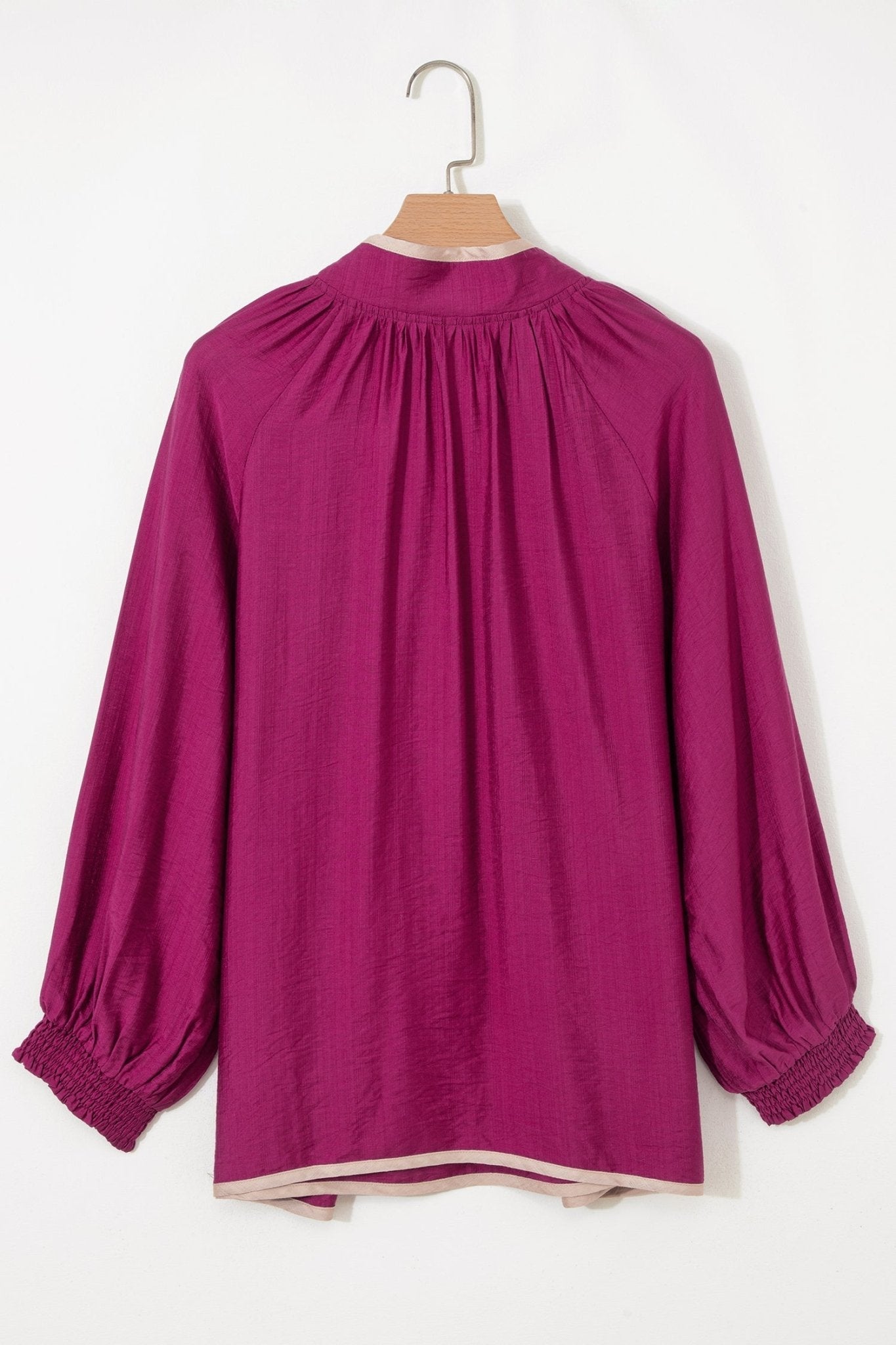 Purple blouse on a hanger against a white background