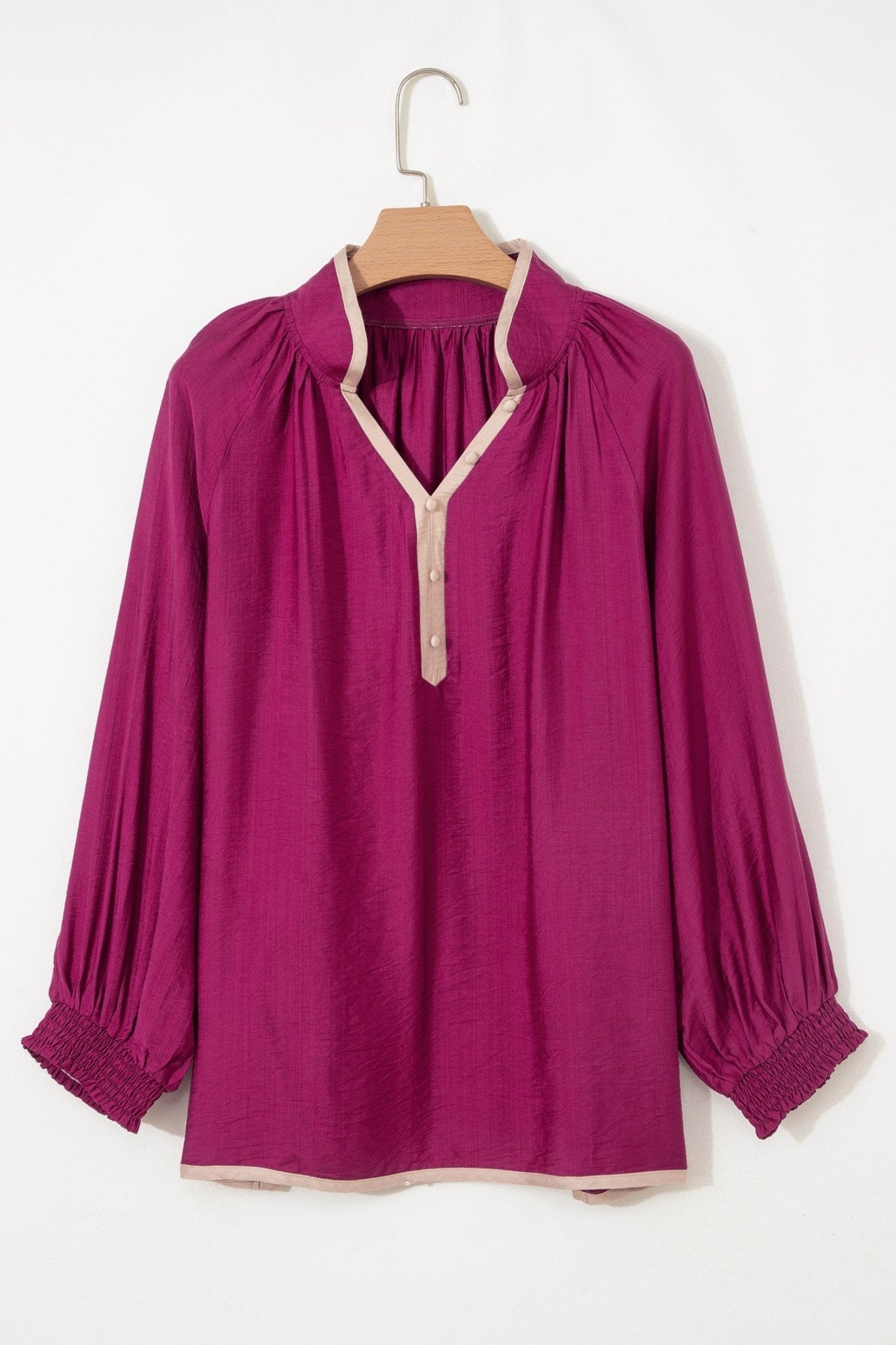 Purple blouse on a wooden hanger against a white background