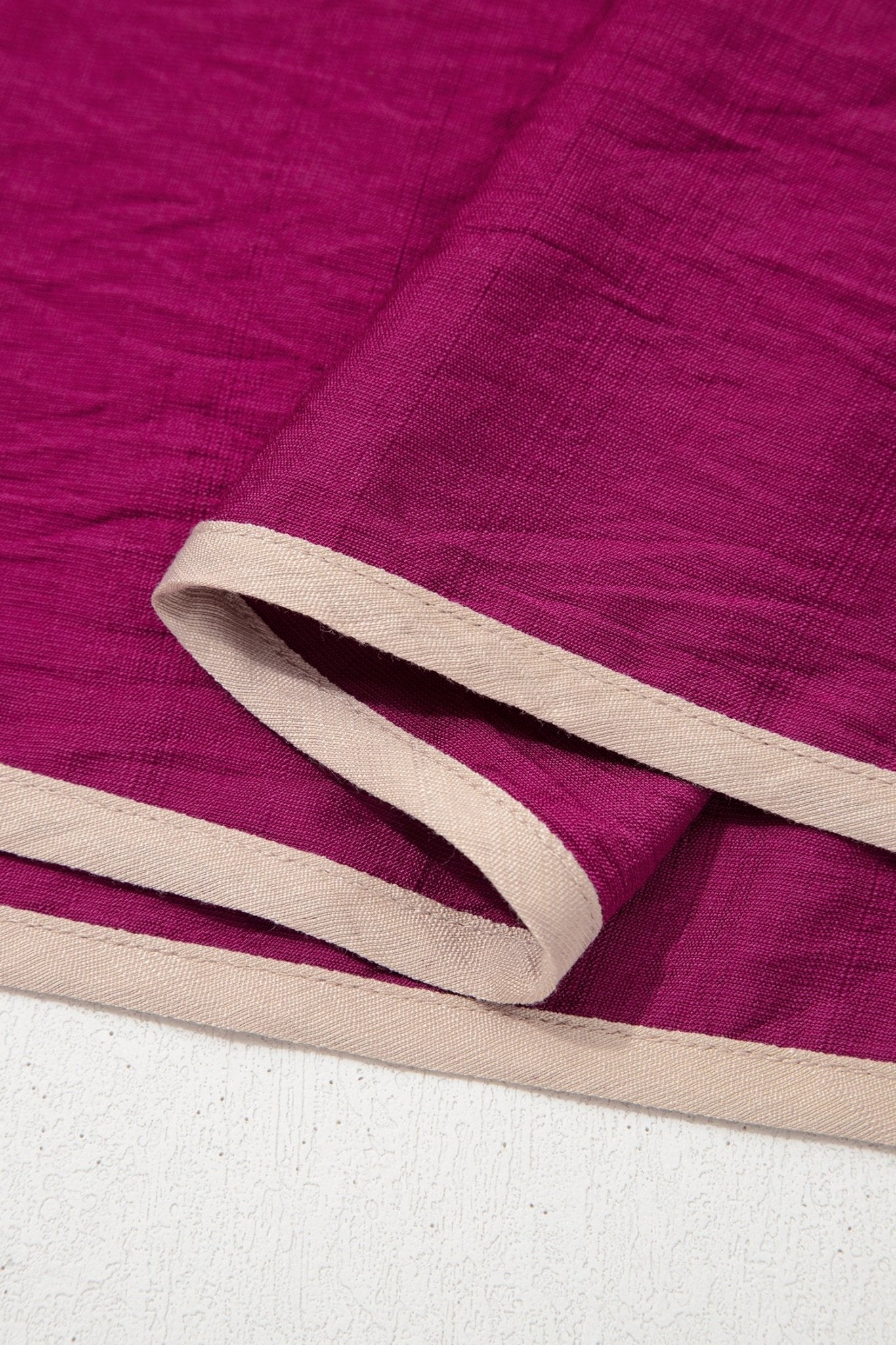 Close-up of purple fabric with beige border on a white background