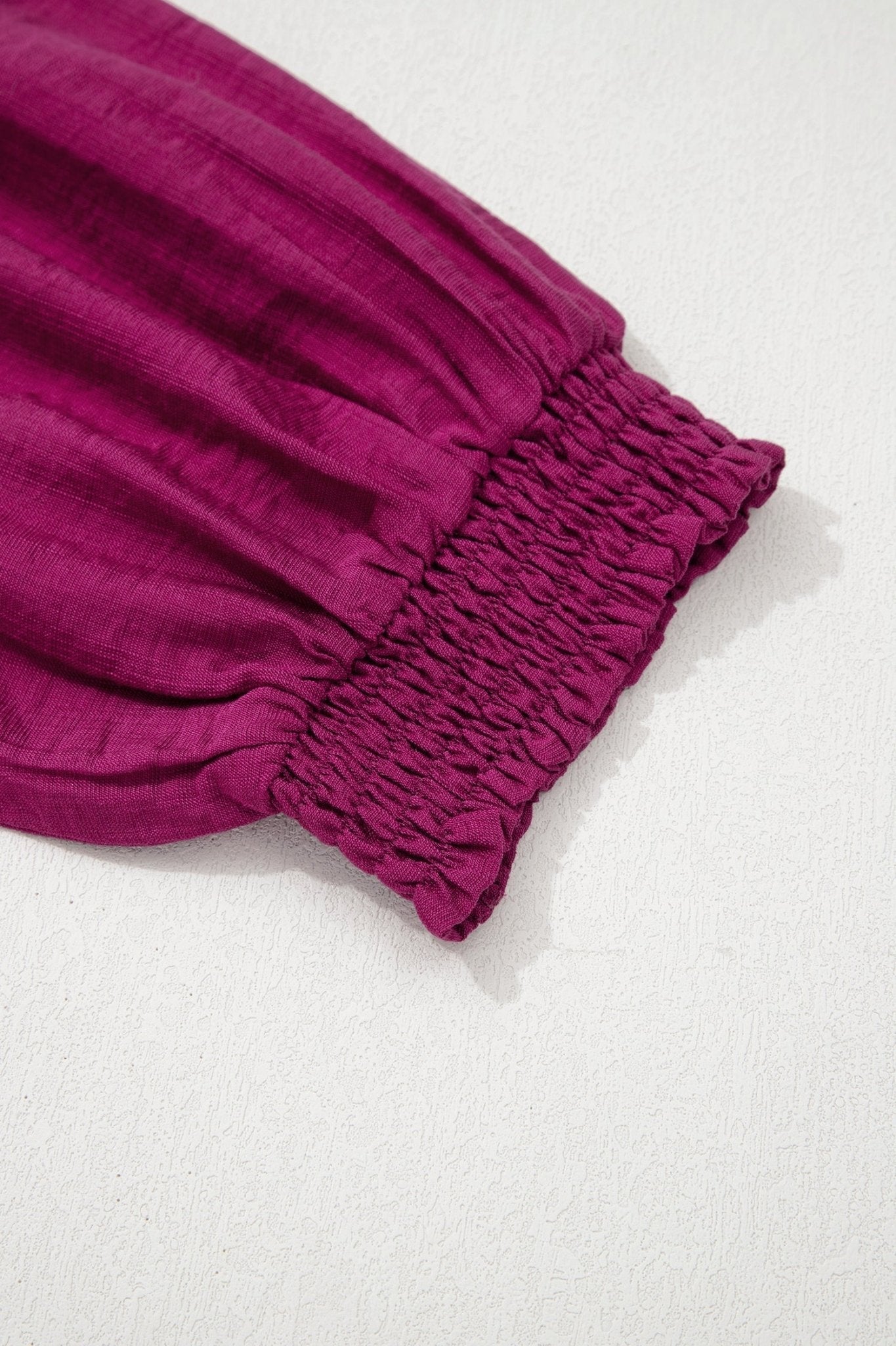Close-up of a magenta fabric with gathered waistband on a white background