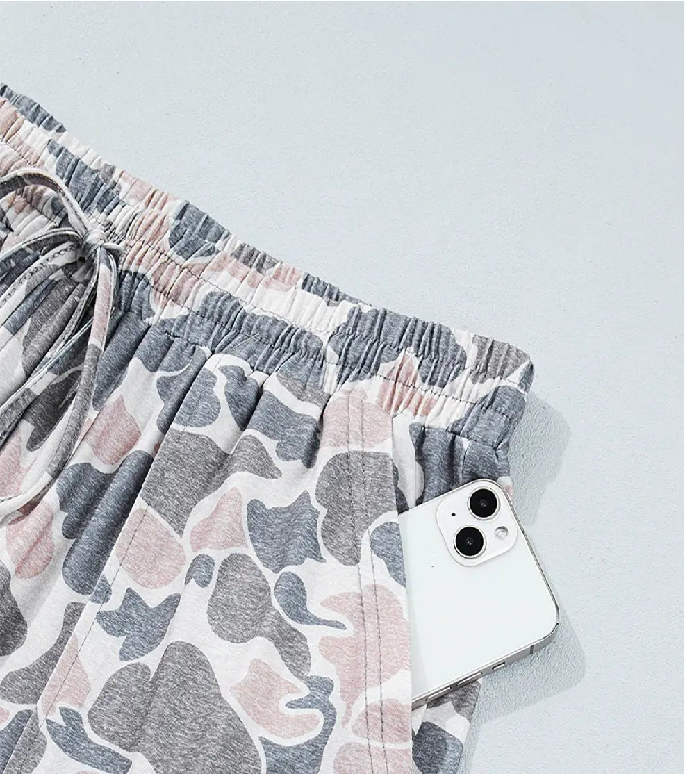 Gray, white, and dusty pink abstract shorts with drawstring waist and smartphone.