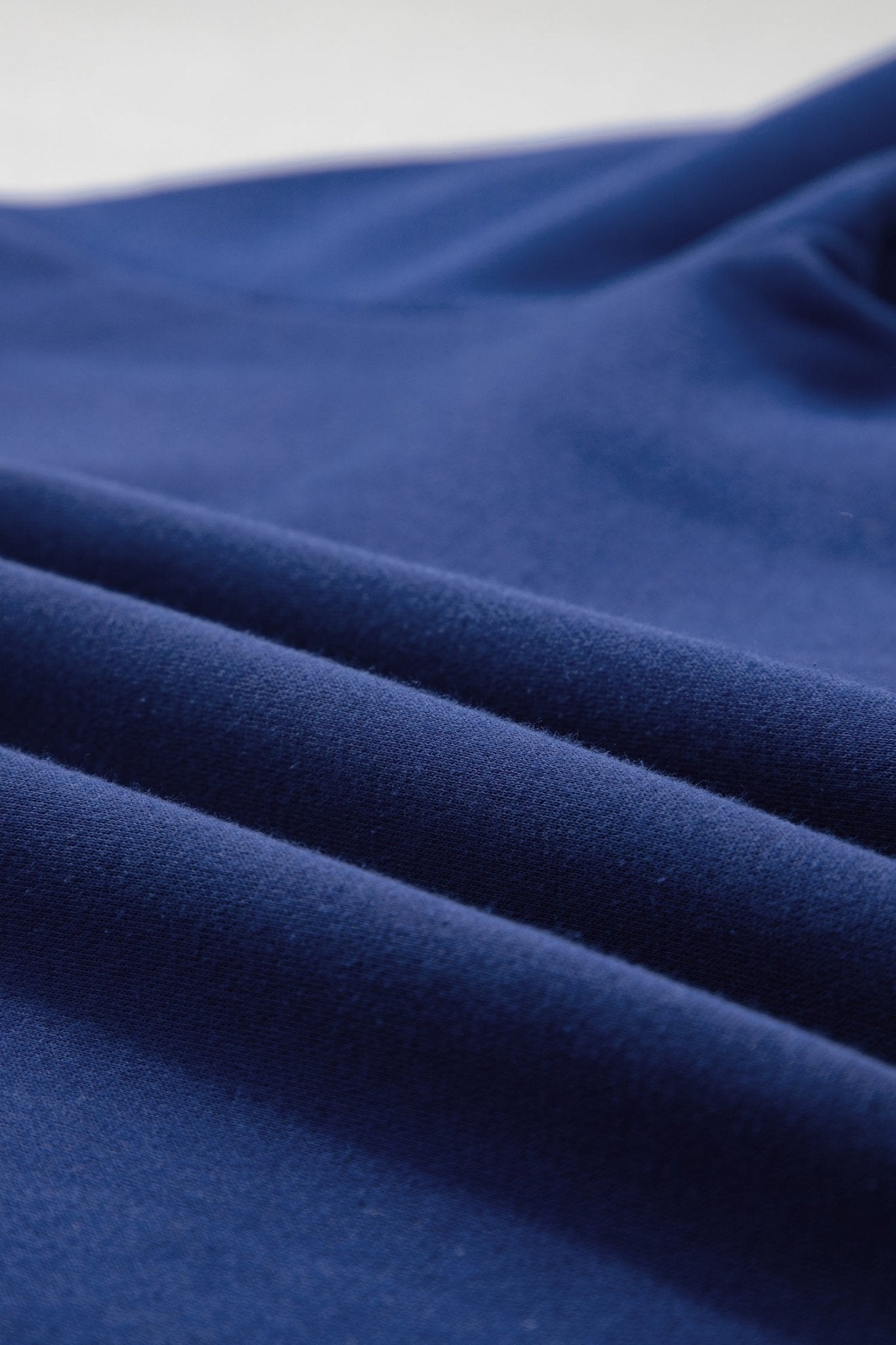 A close-up of draped royal blue fabric with soft folds and a smooth texture.