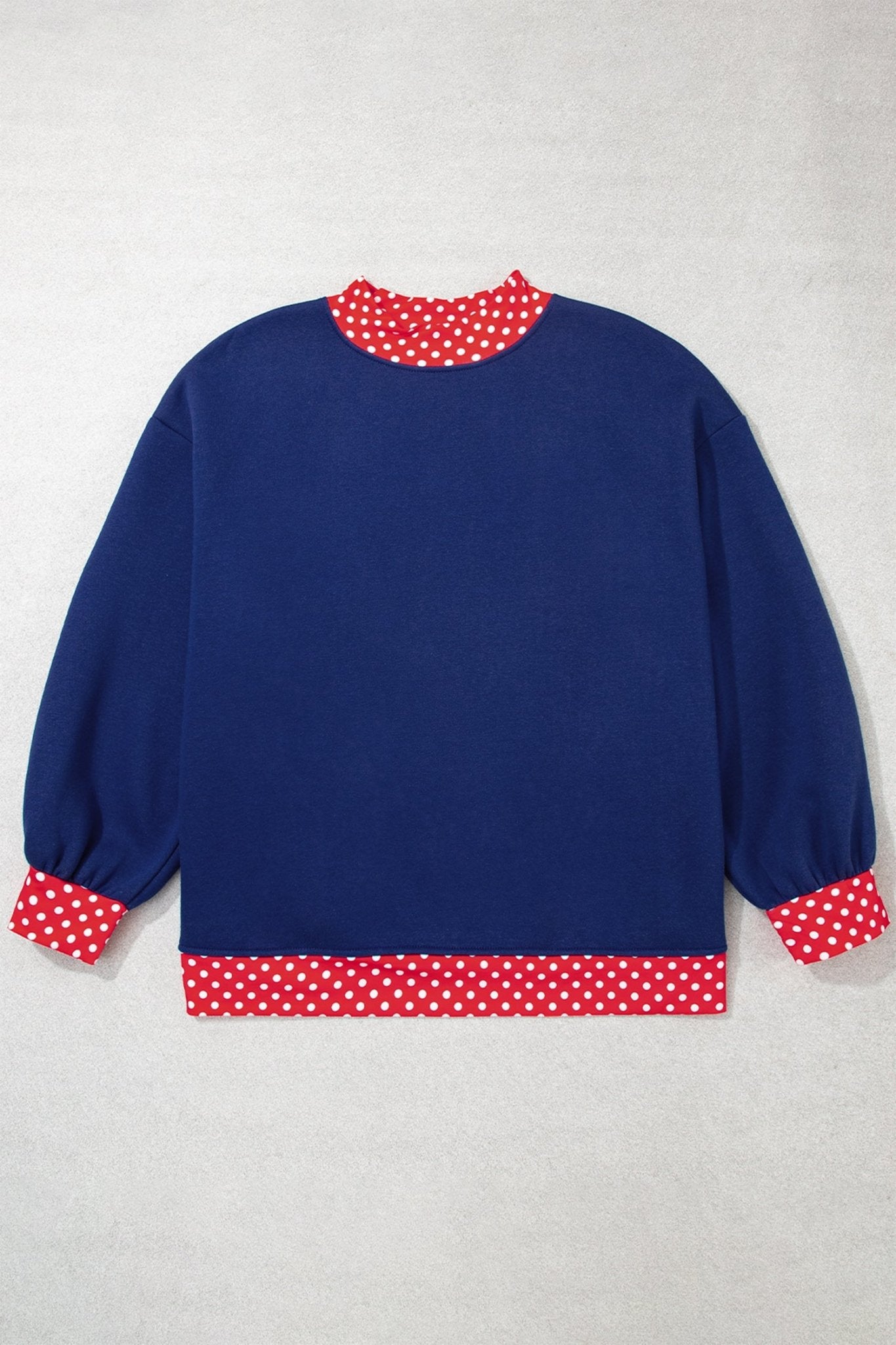 Navy blue long-sleeve sweater with red-white polka-dot trim on collar, cuffs, and hem, flat on light gray.
