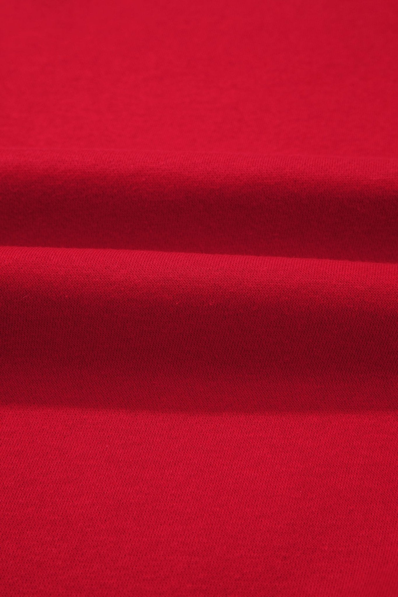 A close-up of bright red fabric with soft horizontal folds showing the material texture.