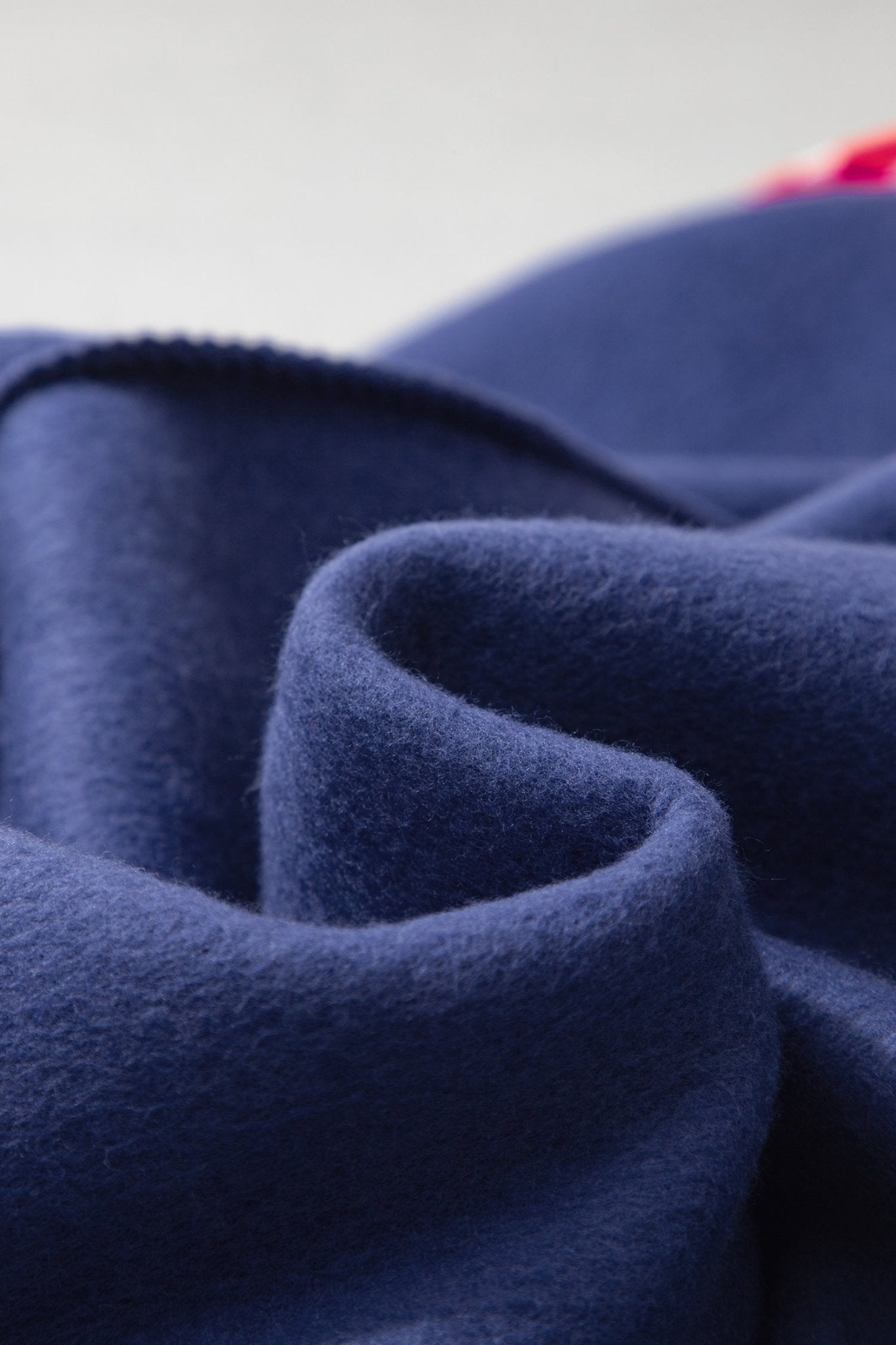 A close-up of draped navy blue fabric with soft folds and a fine, brushed texture.