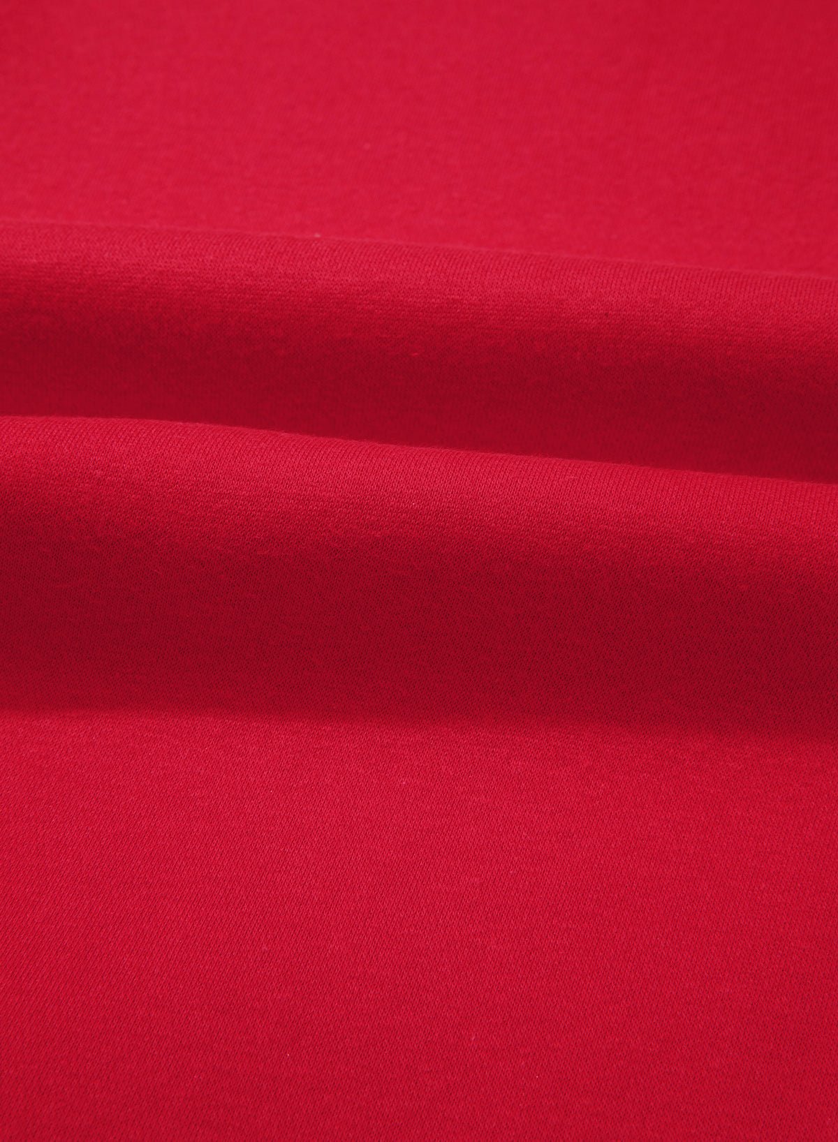 A close-up of bright red fabric with soft horizontal folds showing the material texture.