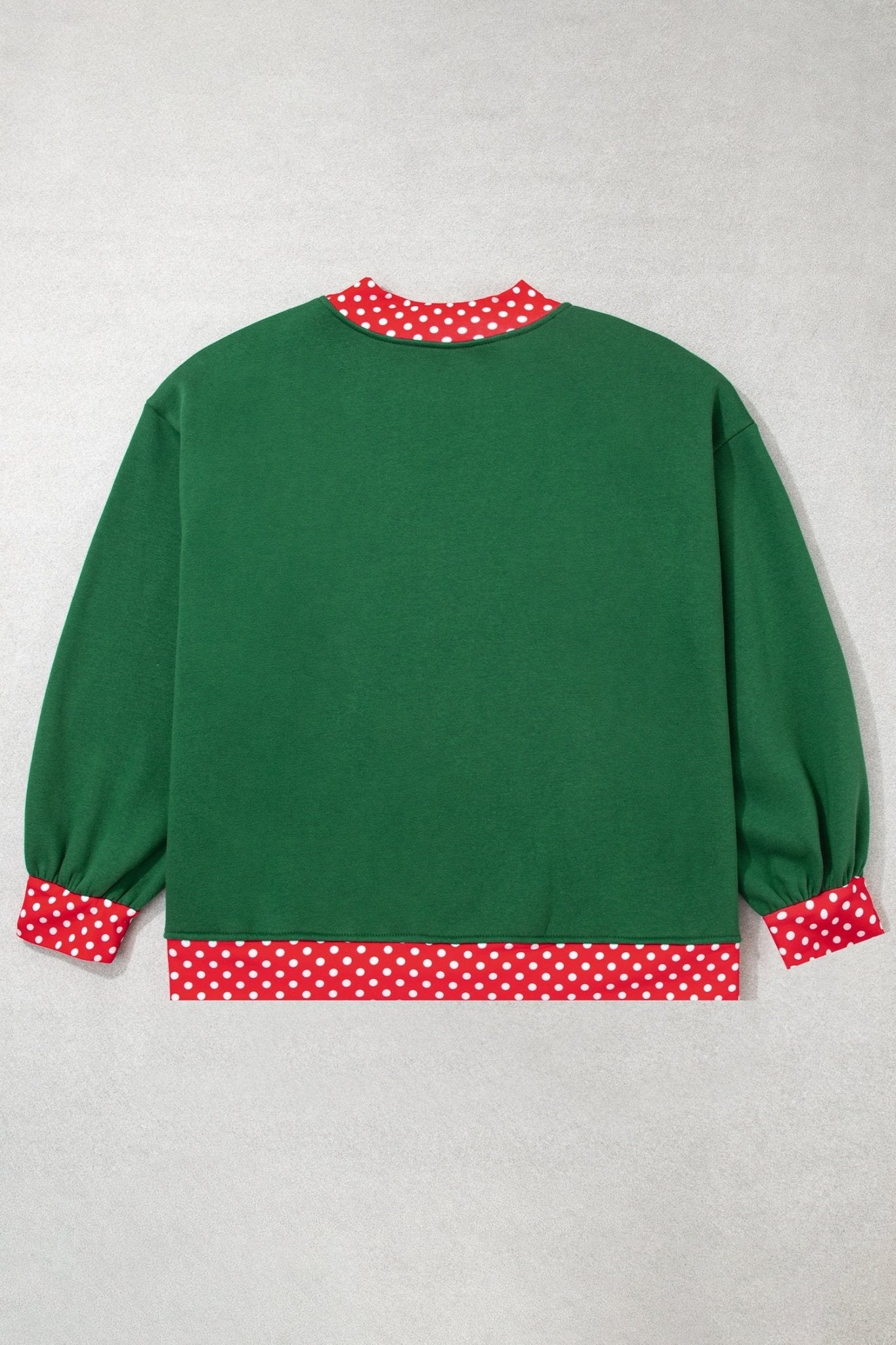 Back view of green long-sleeve top with red-white polka-dot trim on collar and hem, flat on light gray.