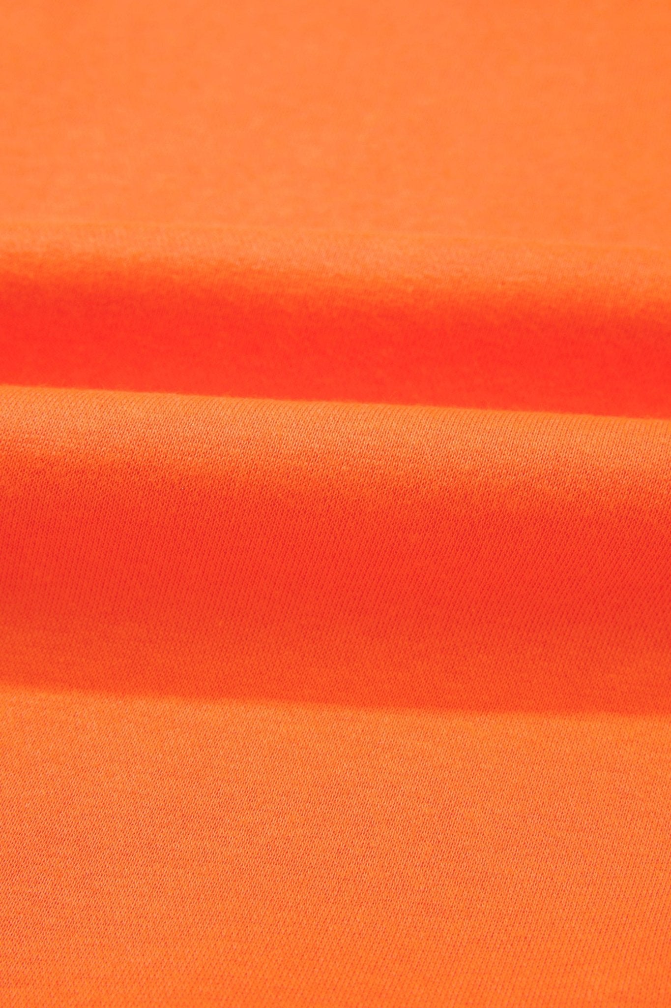 A close-up of bright orange fabric with soft horizontal folds and a smooth texture.
