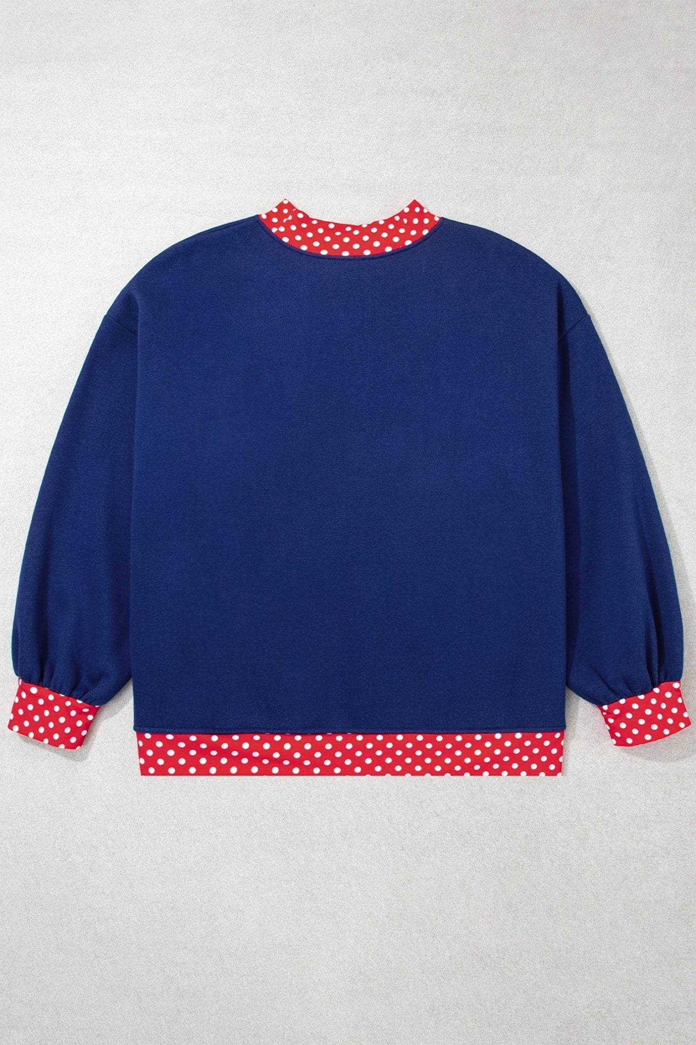 Back view of navy blue long-sleeve sweatshirt with red-white polka-dot trim on collar, cuffs, and hem, flat on gray.