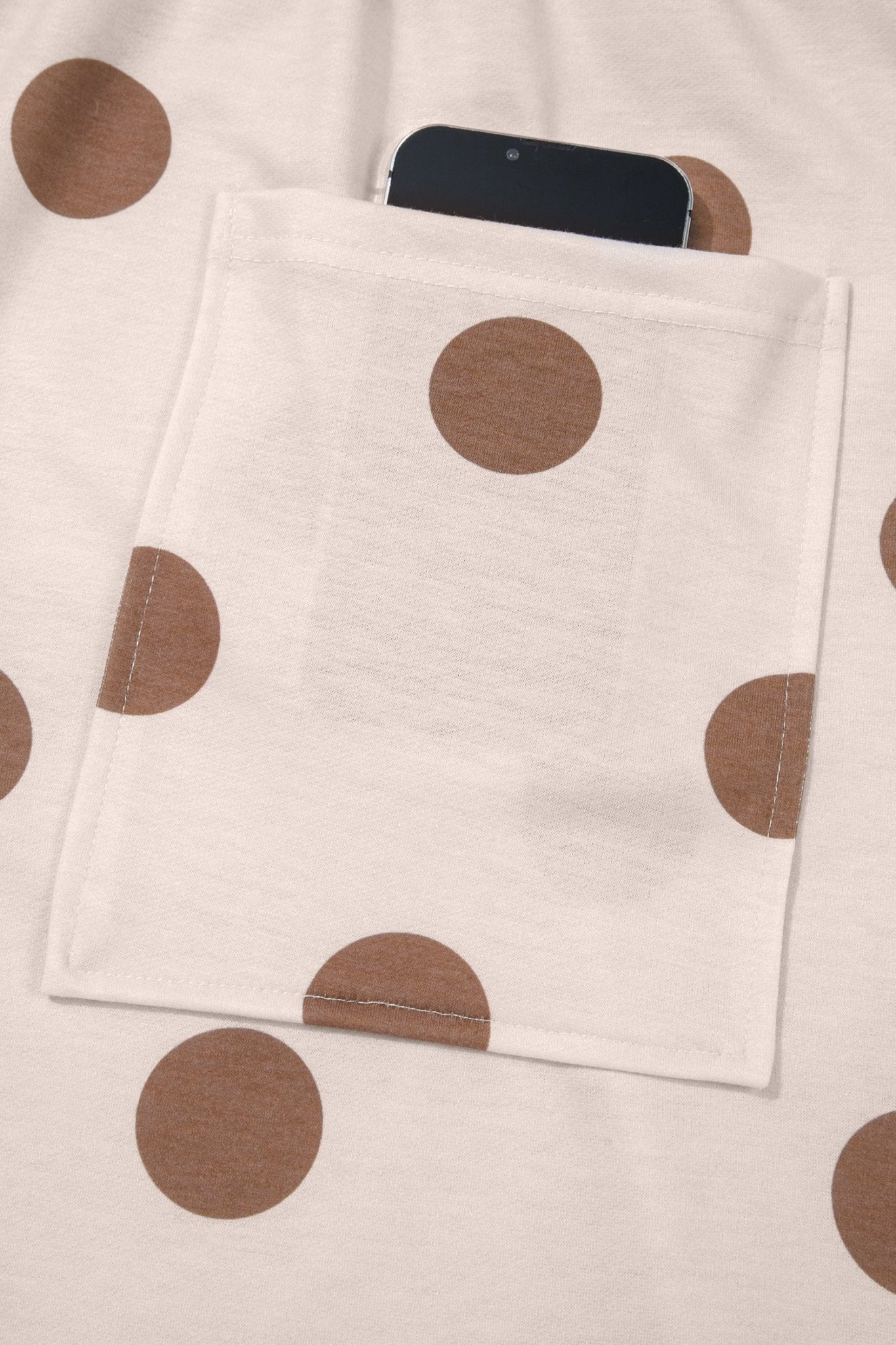 Off-white brown polka dot pouch with black smartphone inside on matching fabric.