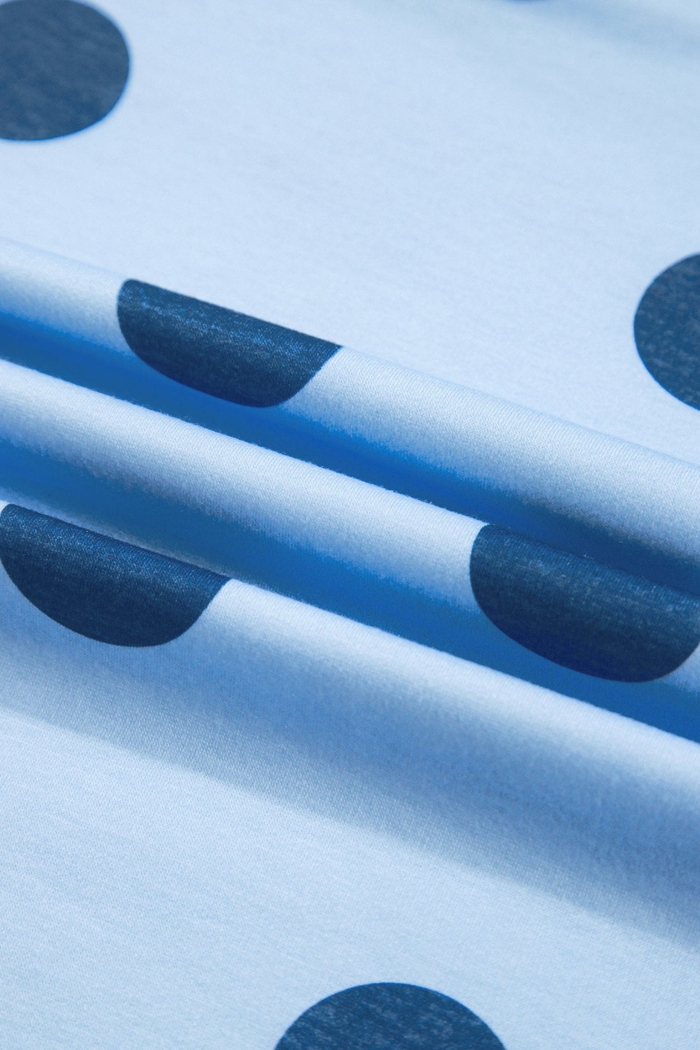 Light blue fabric with a pattern of dark navy blue semi-circles, shown in a close-up with soft folds.