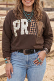 Woman in brown “PRAY” patterned sweatshirt with light blue jeans and turquoise jewelry.