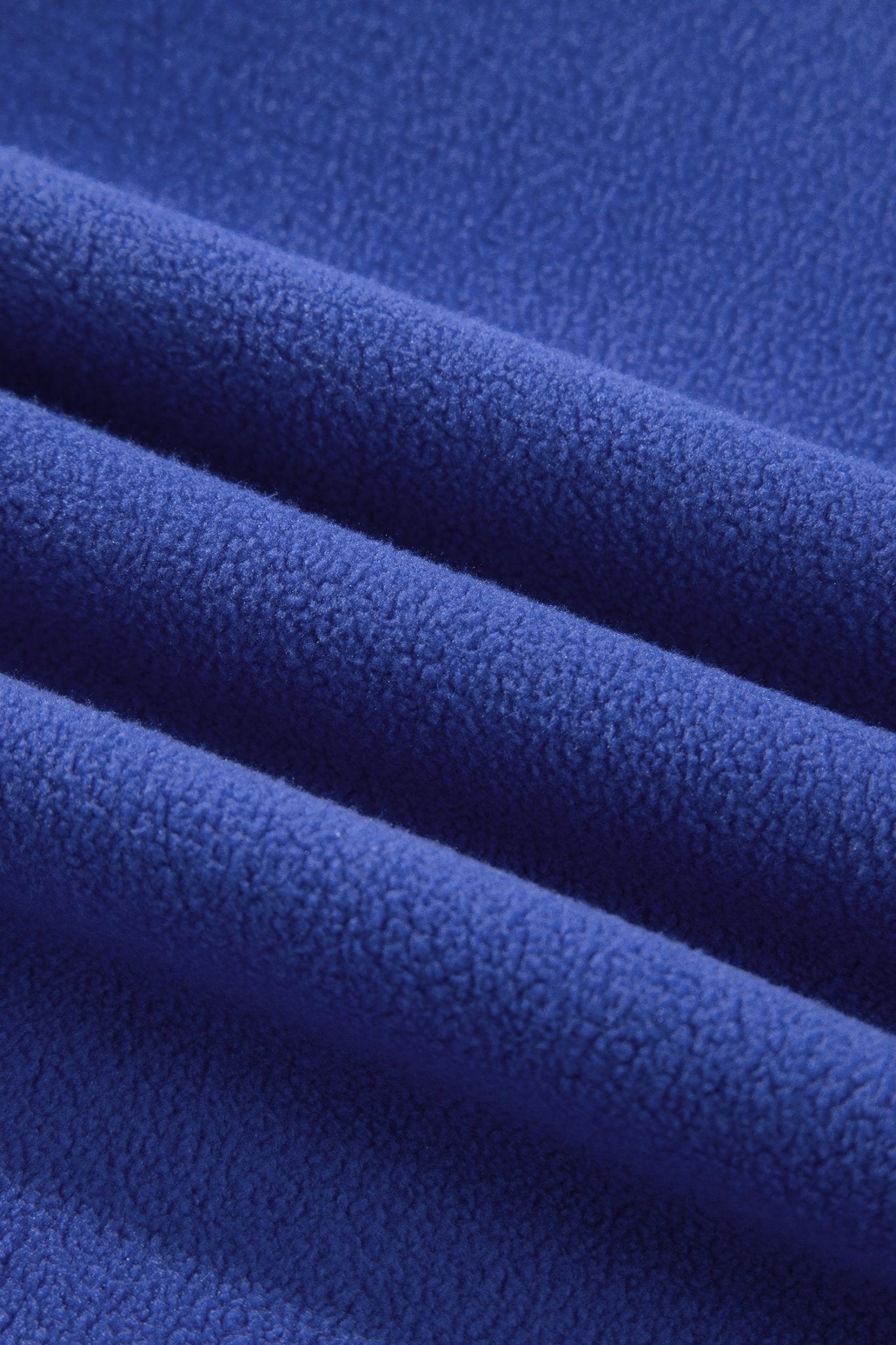 A close-up of folded royal blue fleece fabric showing its soft, textured surface.