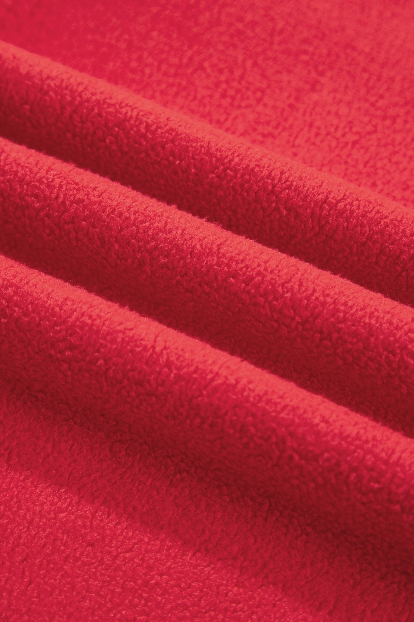 A close-up of bright red textured fabric with soft folds and a plush, terry-like surface.