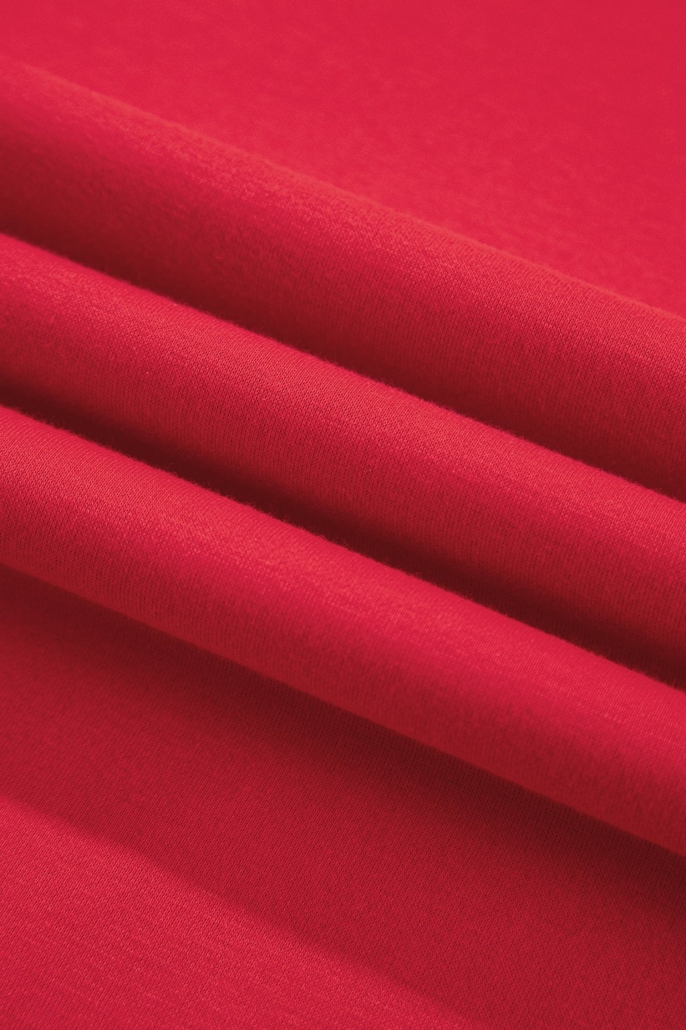 A close-up of bright red fabric with soft diagonal folds showing the material texture.
