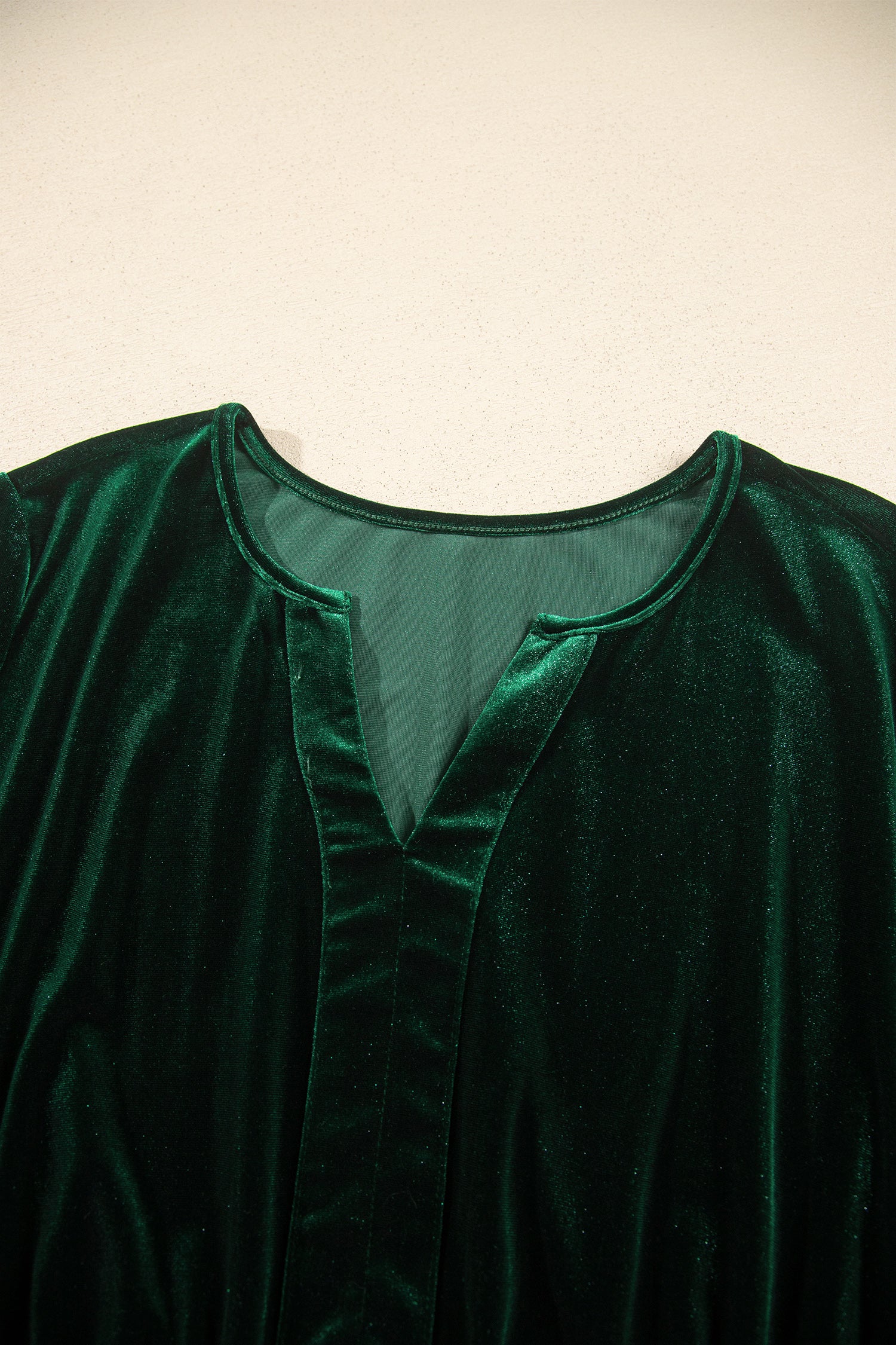 Close-up of notched V neckline on green velvet maxi dress