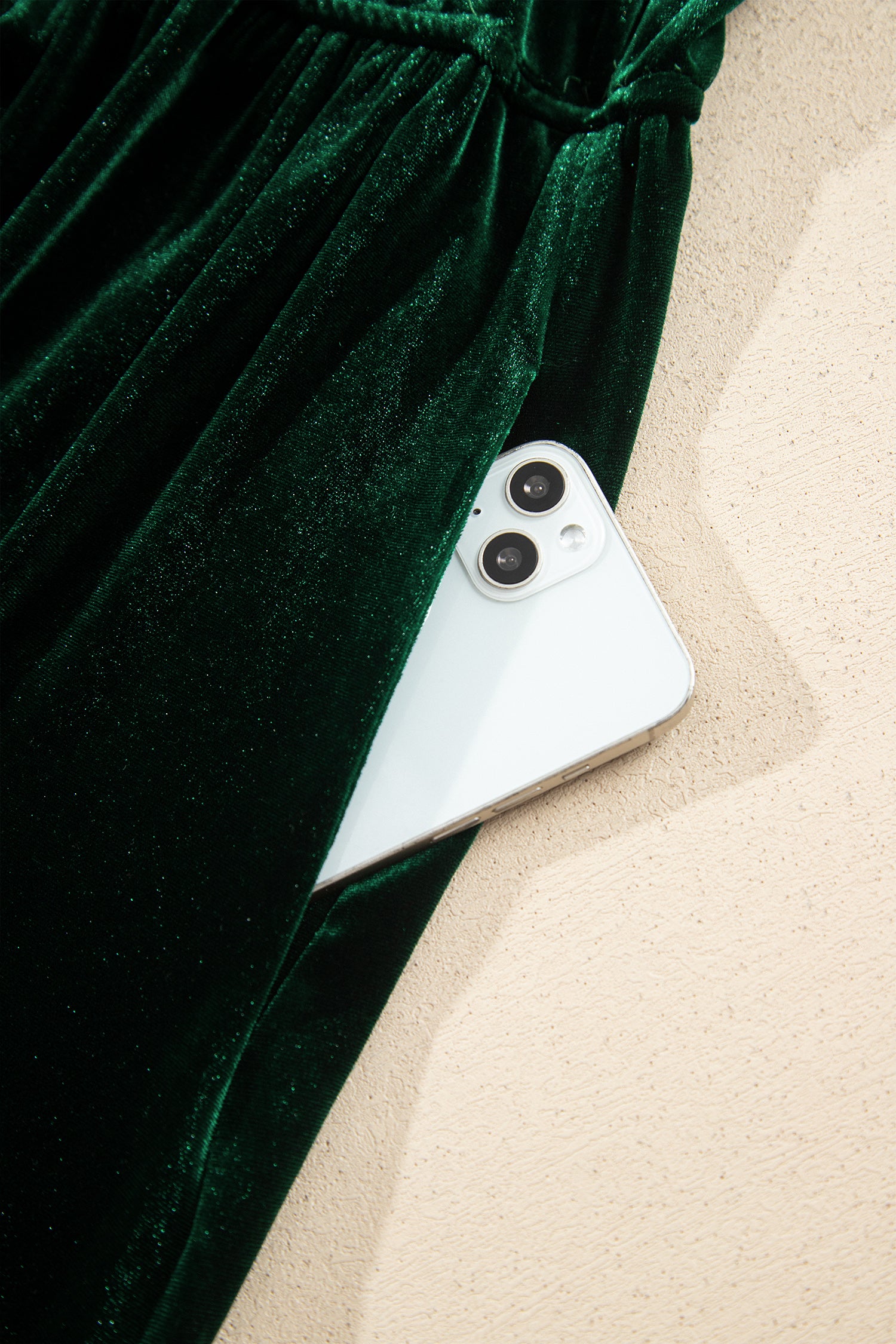 Close-up of side seam pocket holding a phone on green velvet maxi dress