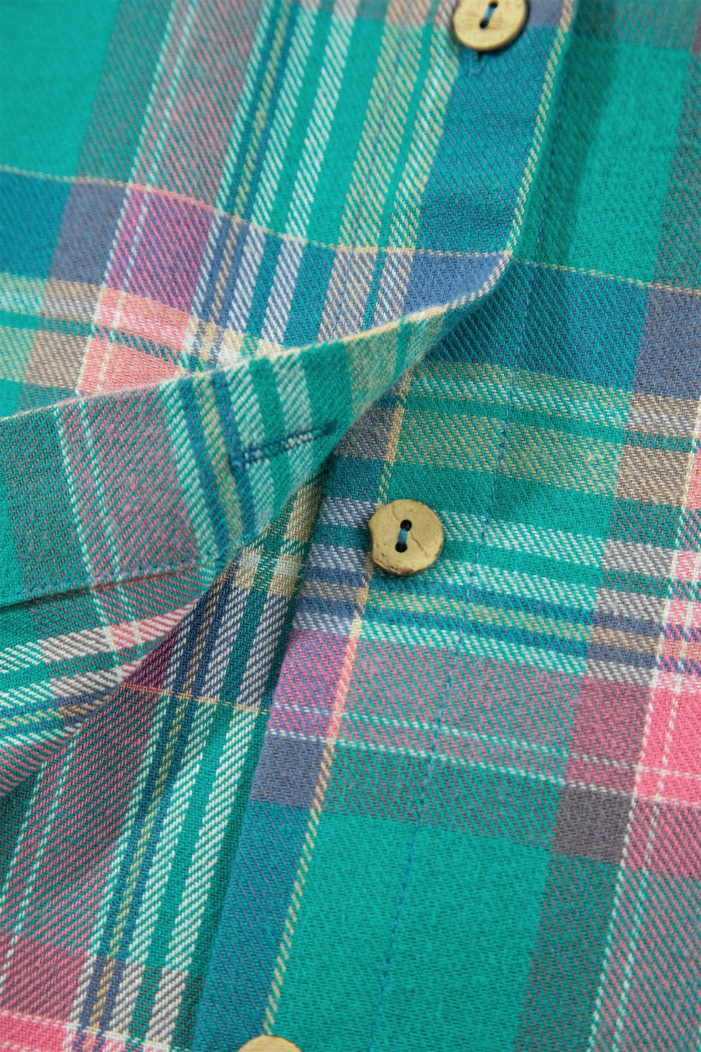 Close-up of a plaid button-up shirt fabric in teal, pink, purple, and white, with visible wooden buttons.