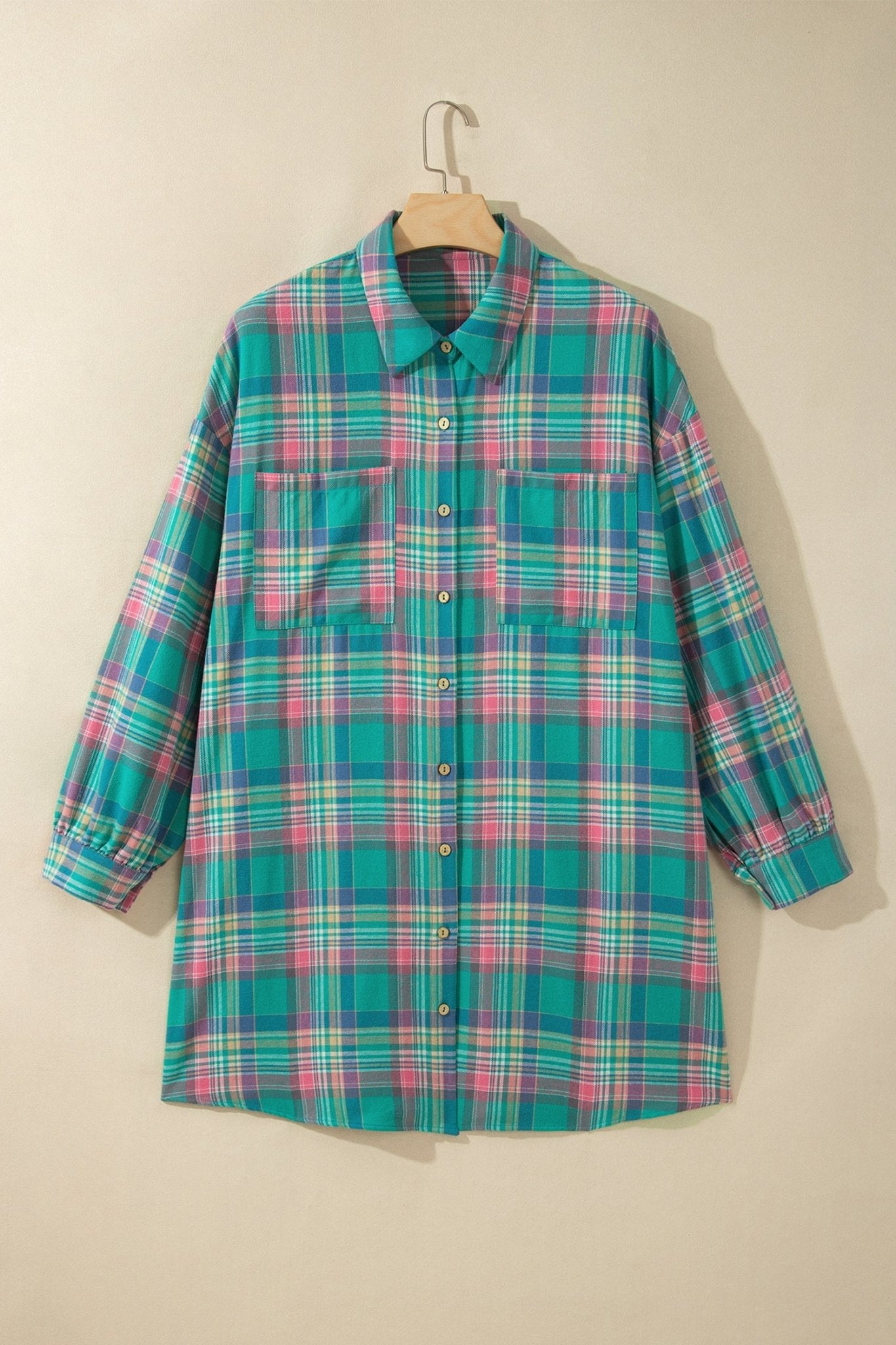 Teal, pink, and white plaid long-sleeve button-up shirt on a wooden hanger.