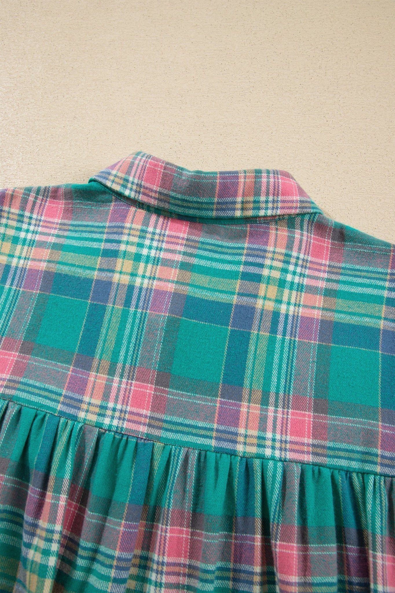 Teal, pink, and blue plaid garment with a ruffled waist seam.