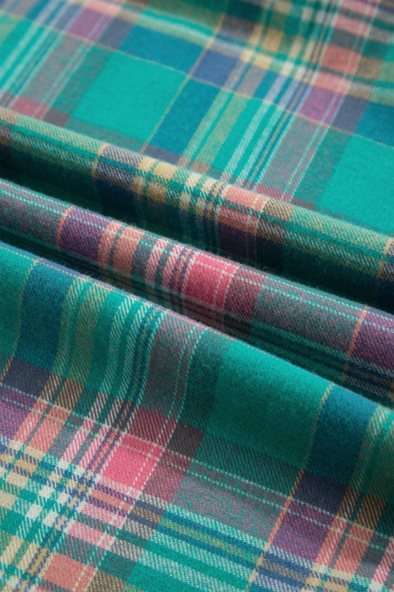 Folded plaid fabric in teal, green, pink, blue, and yellow with woven texture.