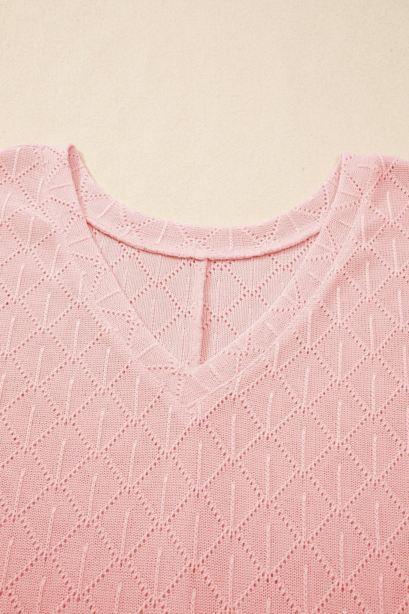 Close-up of a pink textured fabric with a subtle pattern on a beige background