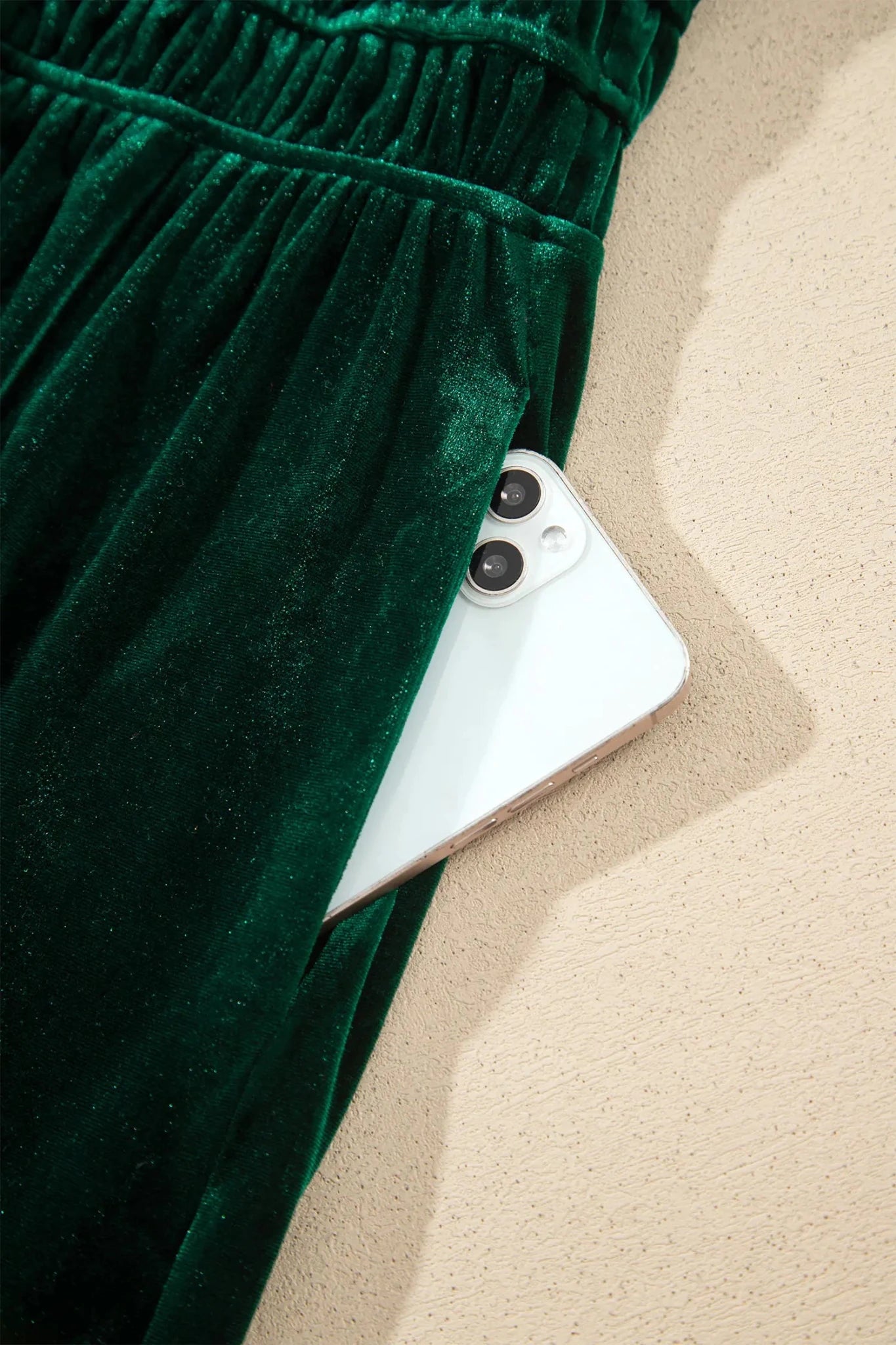 Close-up of dark green velvet garment with elastic waistband and smartphone pocket.