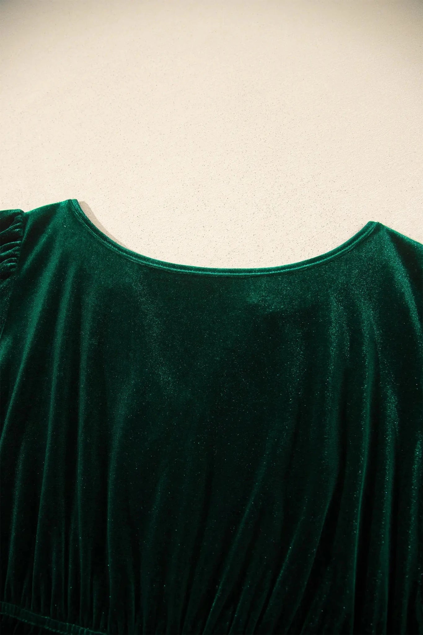 Close-up of dark green velvet garment with rich texture and curved neckline.