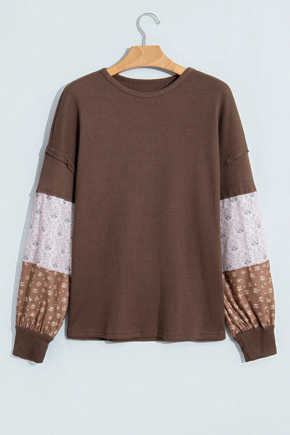 Coffee waffle knit top with floral patchwork sleeves on a hanger, front view