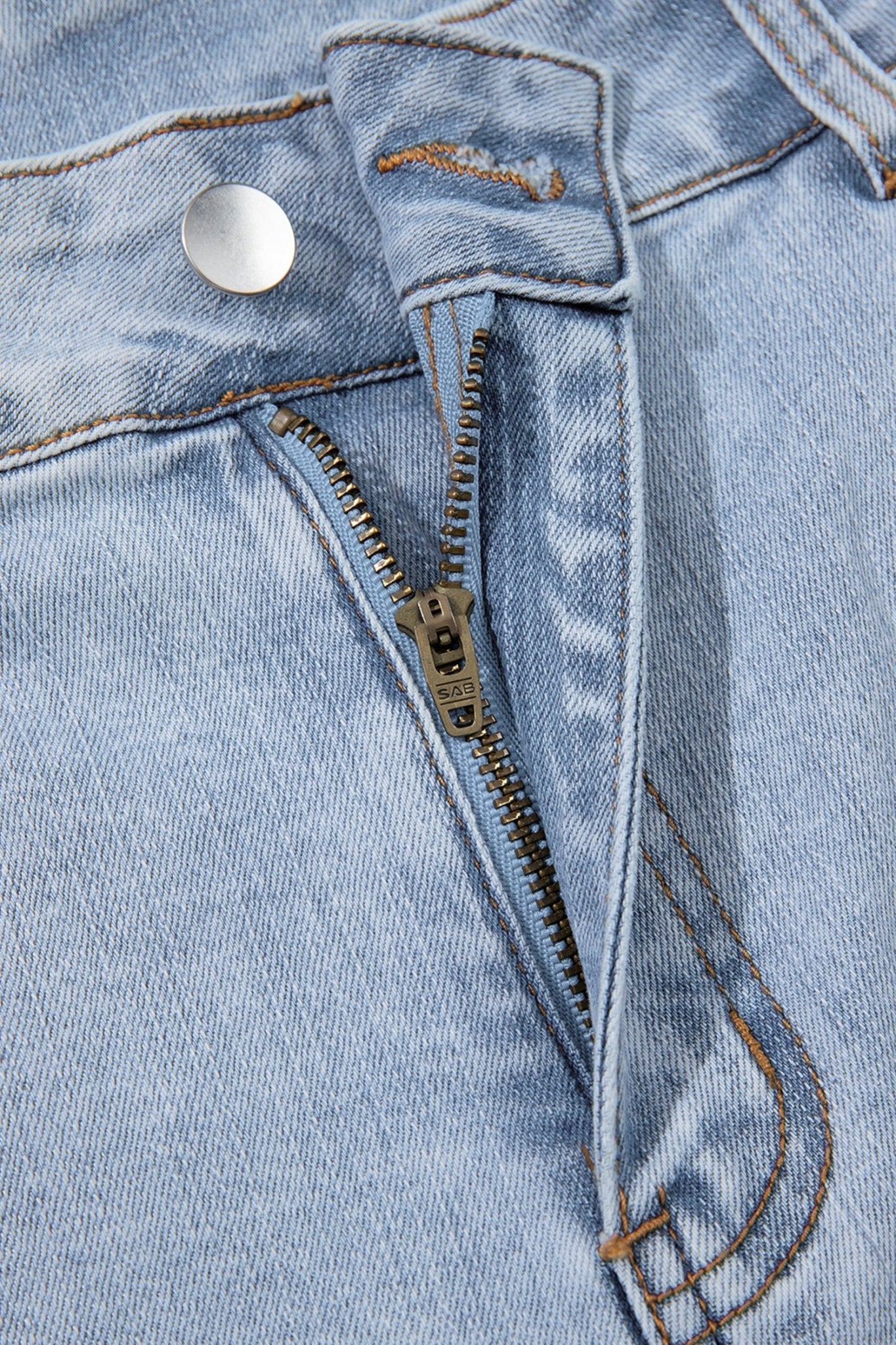 Light blue cropped jeans with diagonal seams on a wooden hanger.