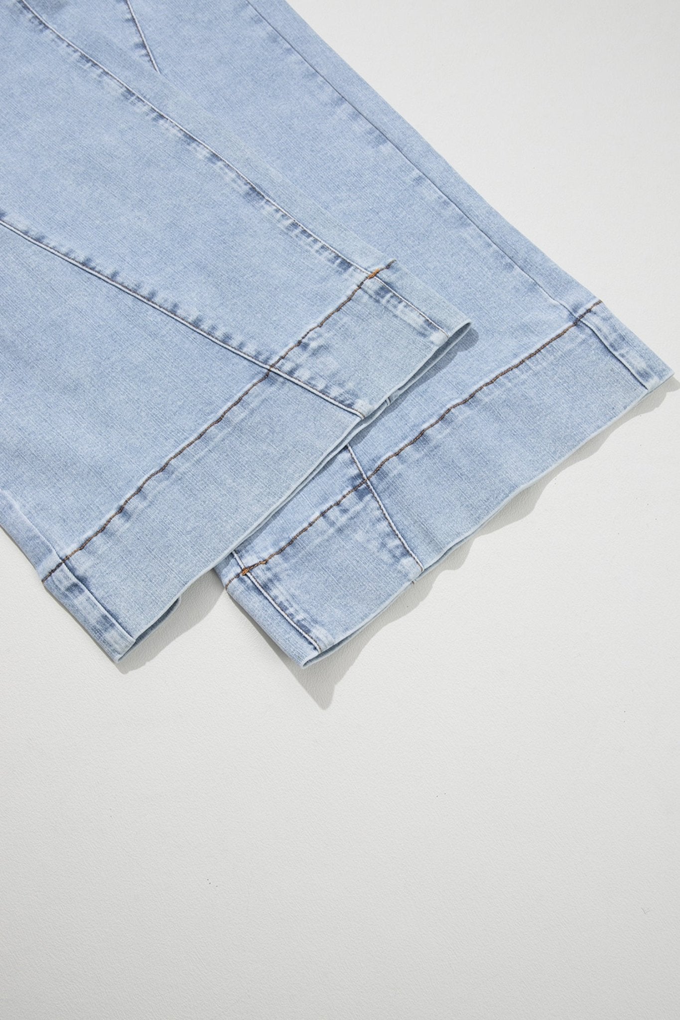 Light blue denim with folded fabric, seams, and contrast stitching.