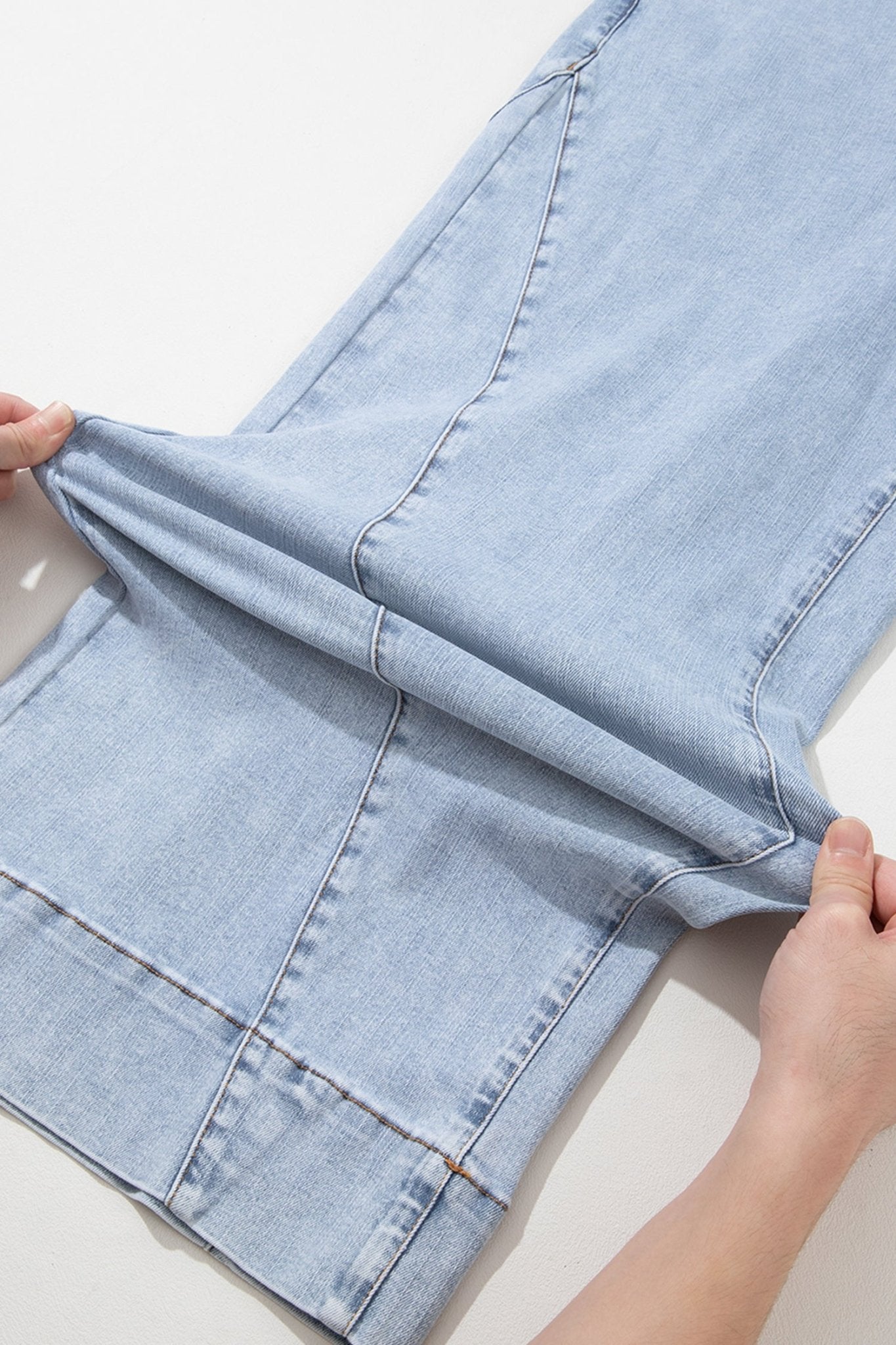 Light blue cropped jeans with diagonal seams on a wooden hanger.