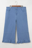 Light blue wide-leg denim pants with ruffled hems, hanging on a wooden hanger against an off-white background.