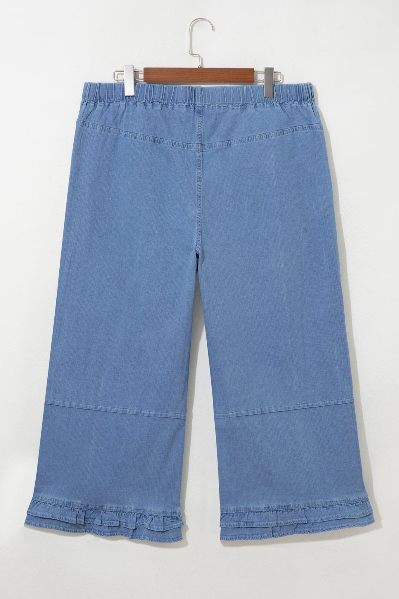 Light blue denim cropped pants with ruffle hems and elastic waist on hanger.
