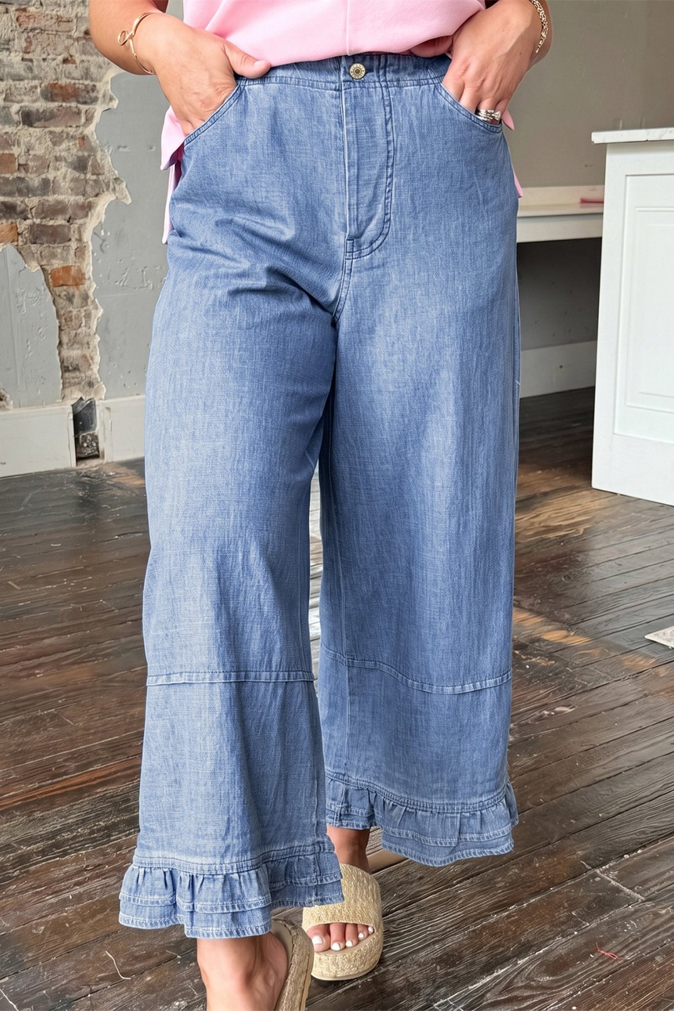 Woman in pink top, light blue ruffle-hem wide jeans, beige espadrille sandals.