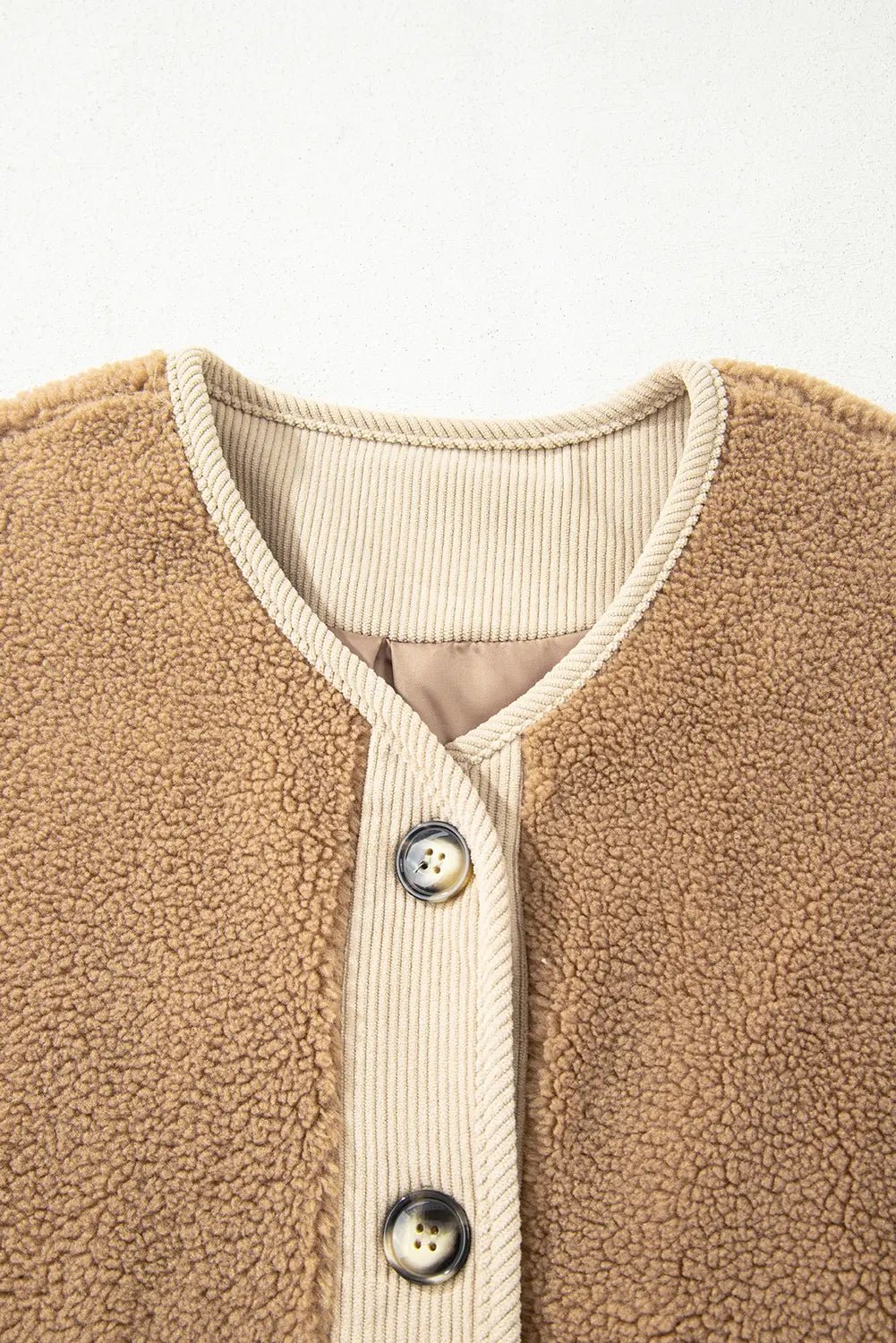 Close-up of a brown fleece jacket with button details on a white background